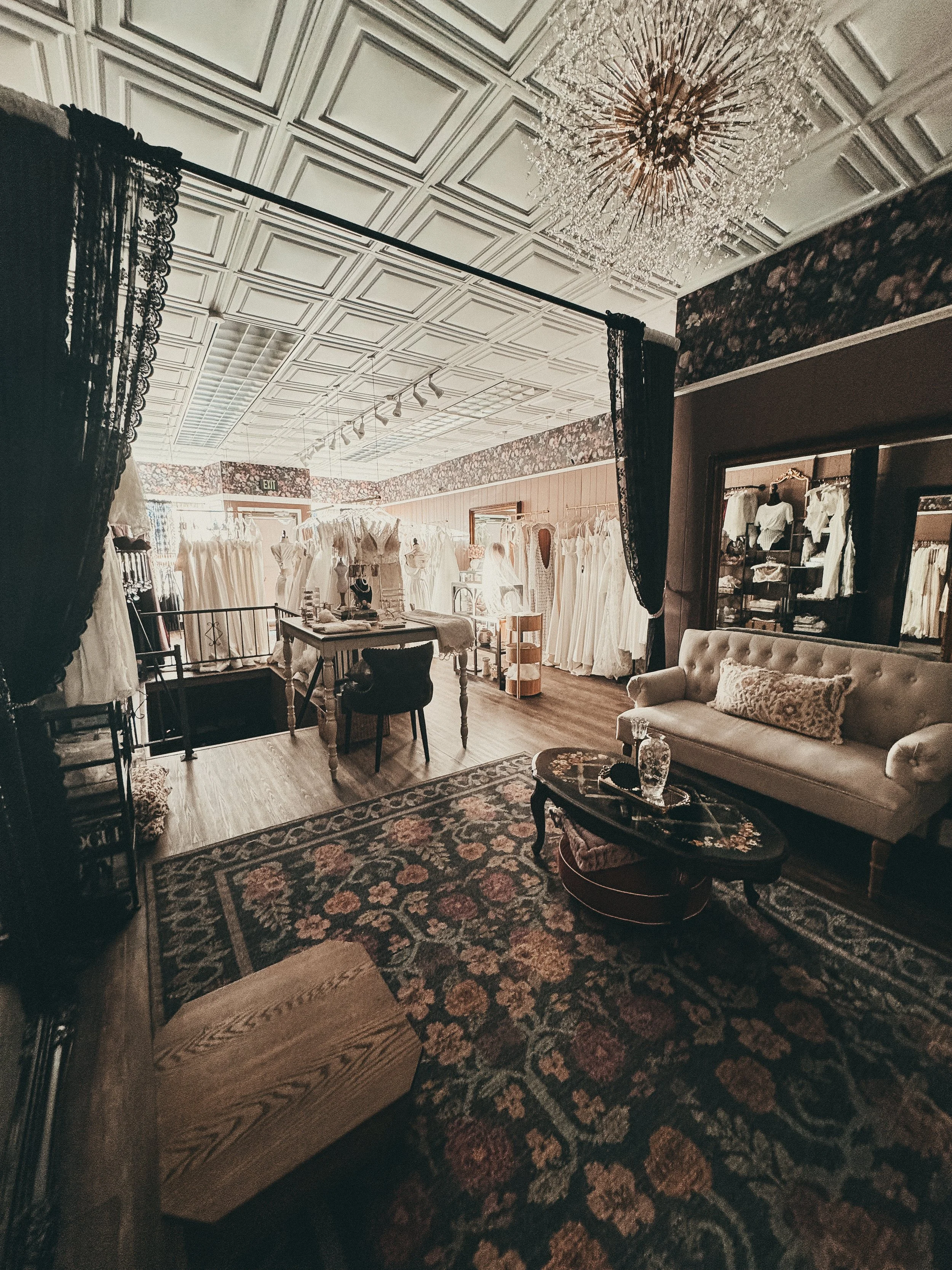 The Art & Lace bridal studio in Somerset, Massachusetts — tin ceilings, a sunburst chandelier, tufted sofa, and Persian rug in the private appointment space.