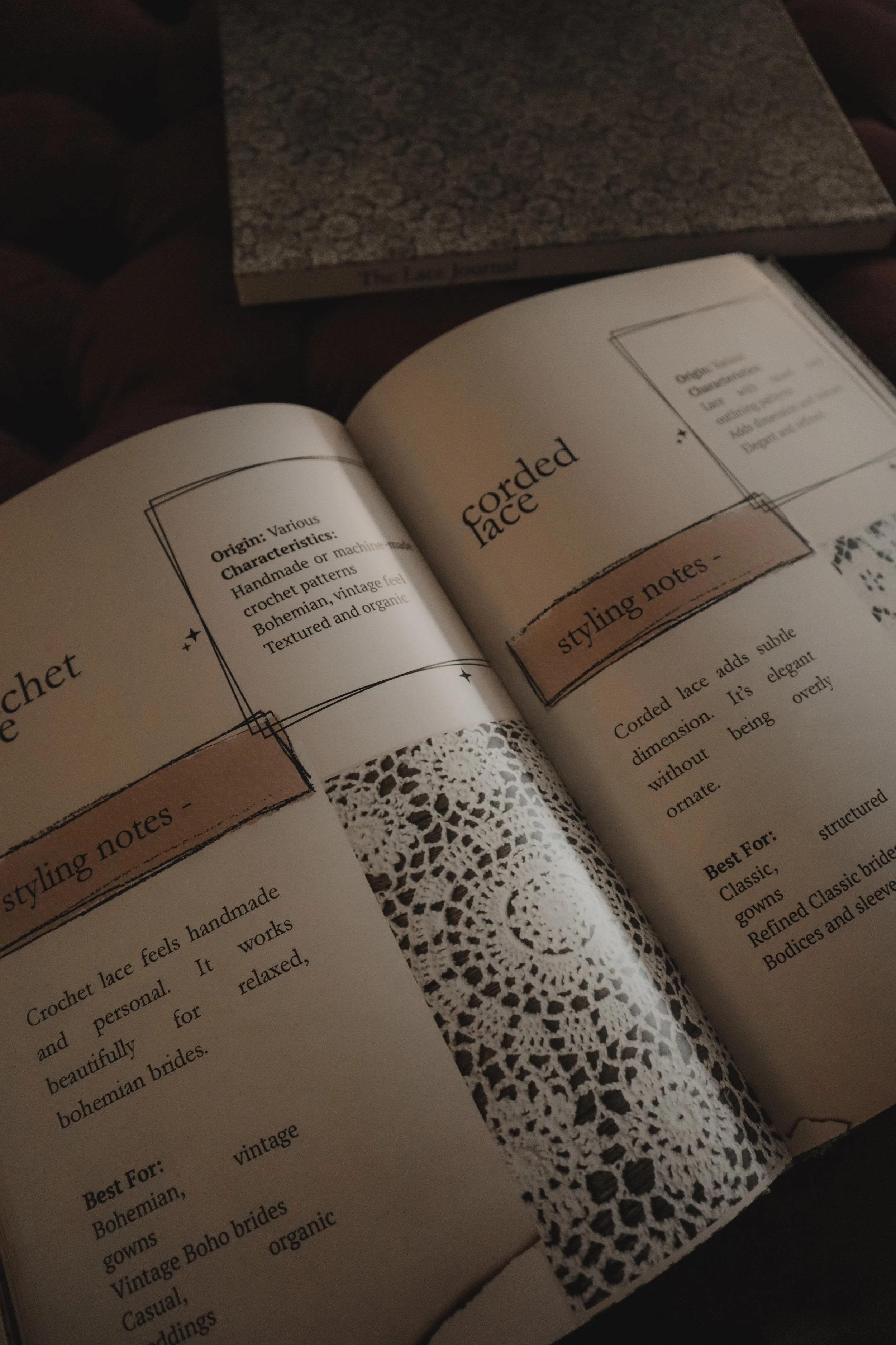 Open book with text about corded lace on a dark surface, with a gray textured book in the background.