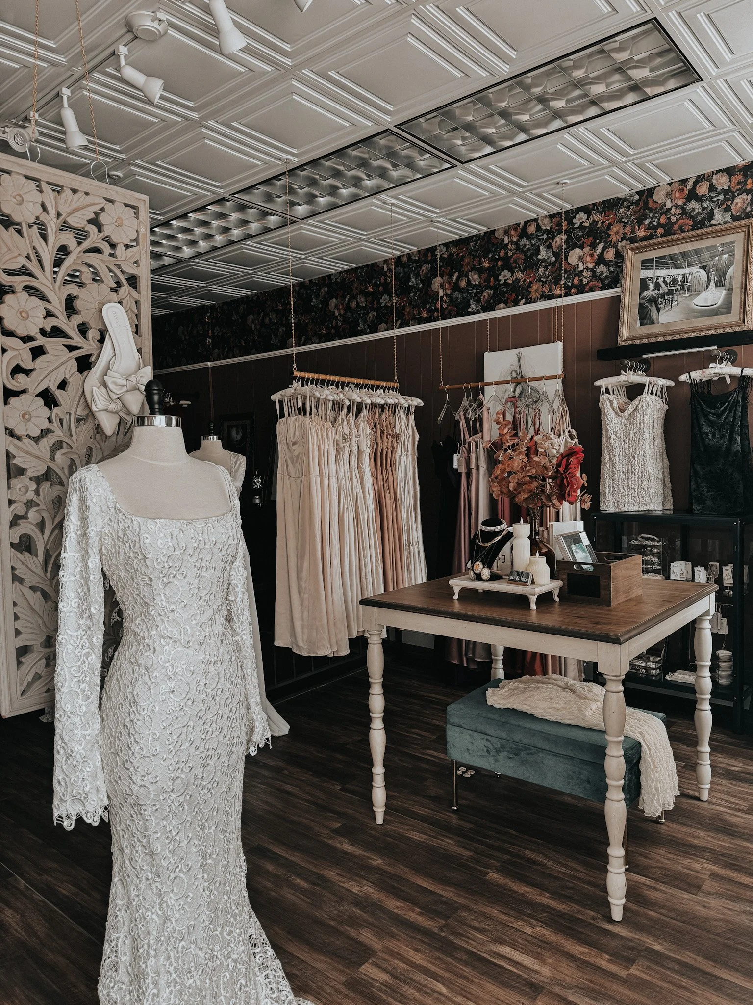 Interior of a bridal boutique with wedding dresses on display, mannequin wearing a lace wedding gown, and vintage-style decor.