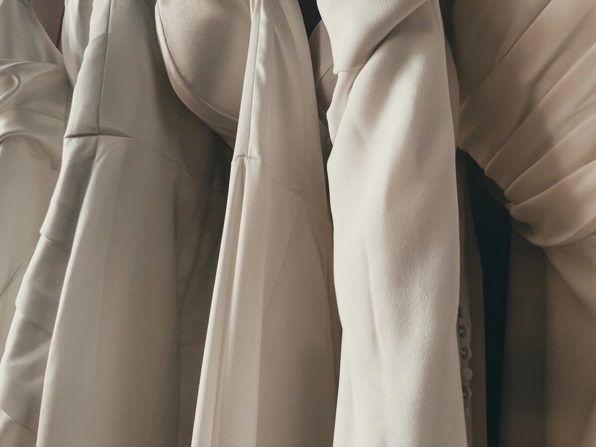 Clean satin neckline and pleated bodice of a modern minimalist bridal gown at Art & Lace Bridal, Massachusetts.