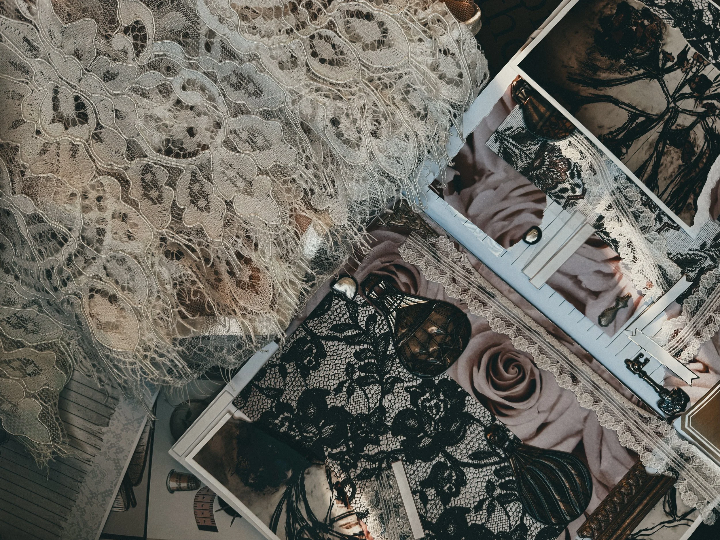 A collection of lace fabrics, lace jewelry, and mirrors arranged on a surface with a fabric background.