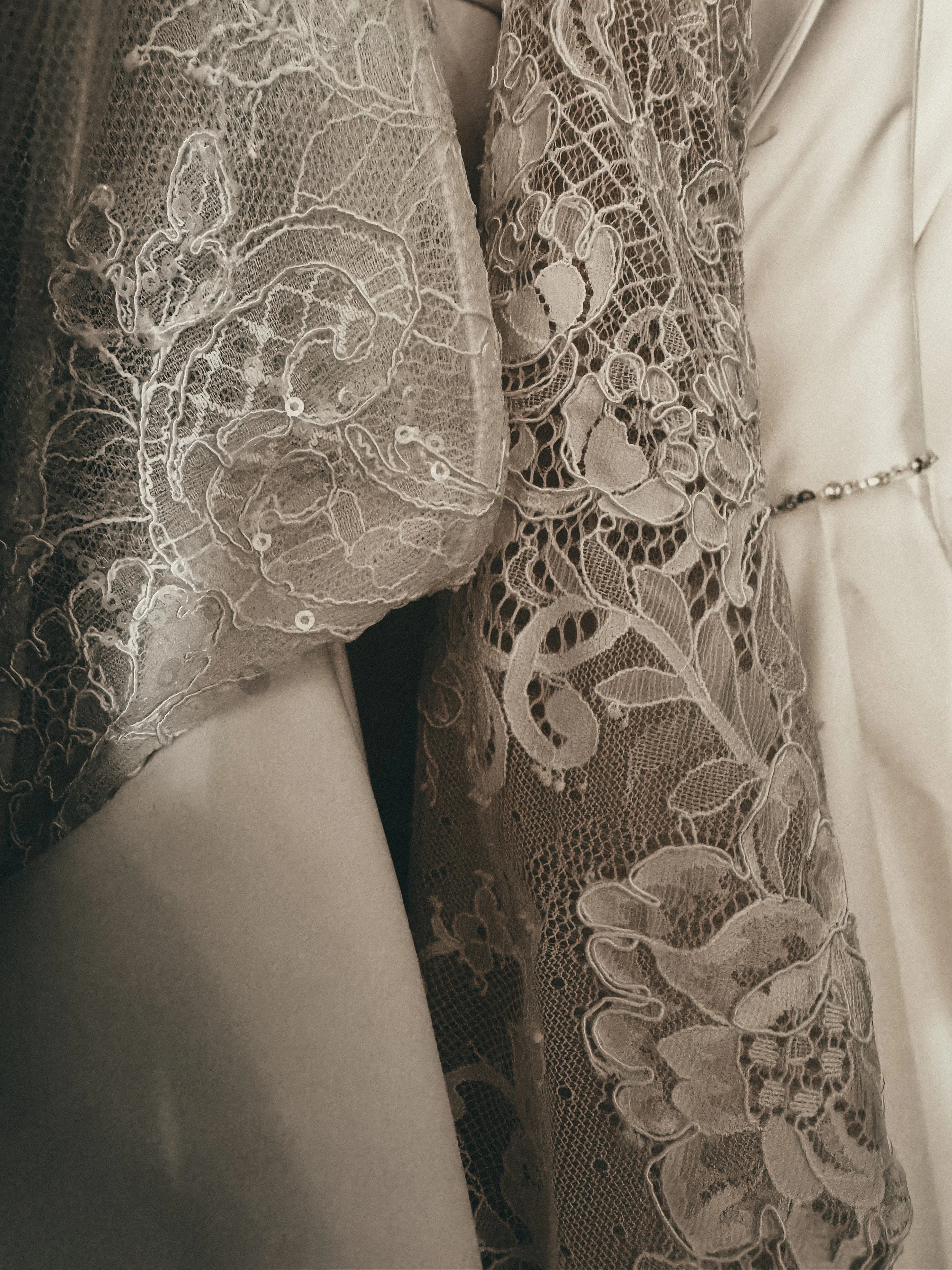 Close-up of hand-appliqué lace sleeve and satin gown at Art & Lace Bridal in Somerset, MA — Romantic Heirloom realm detail.