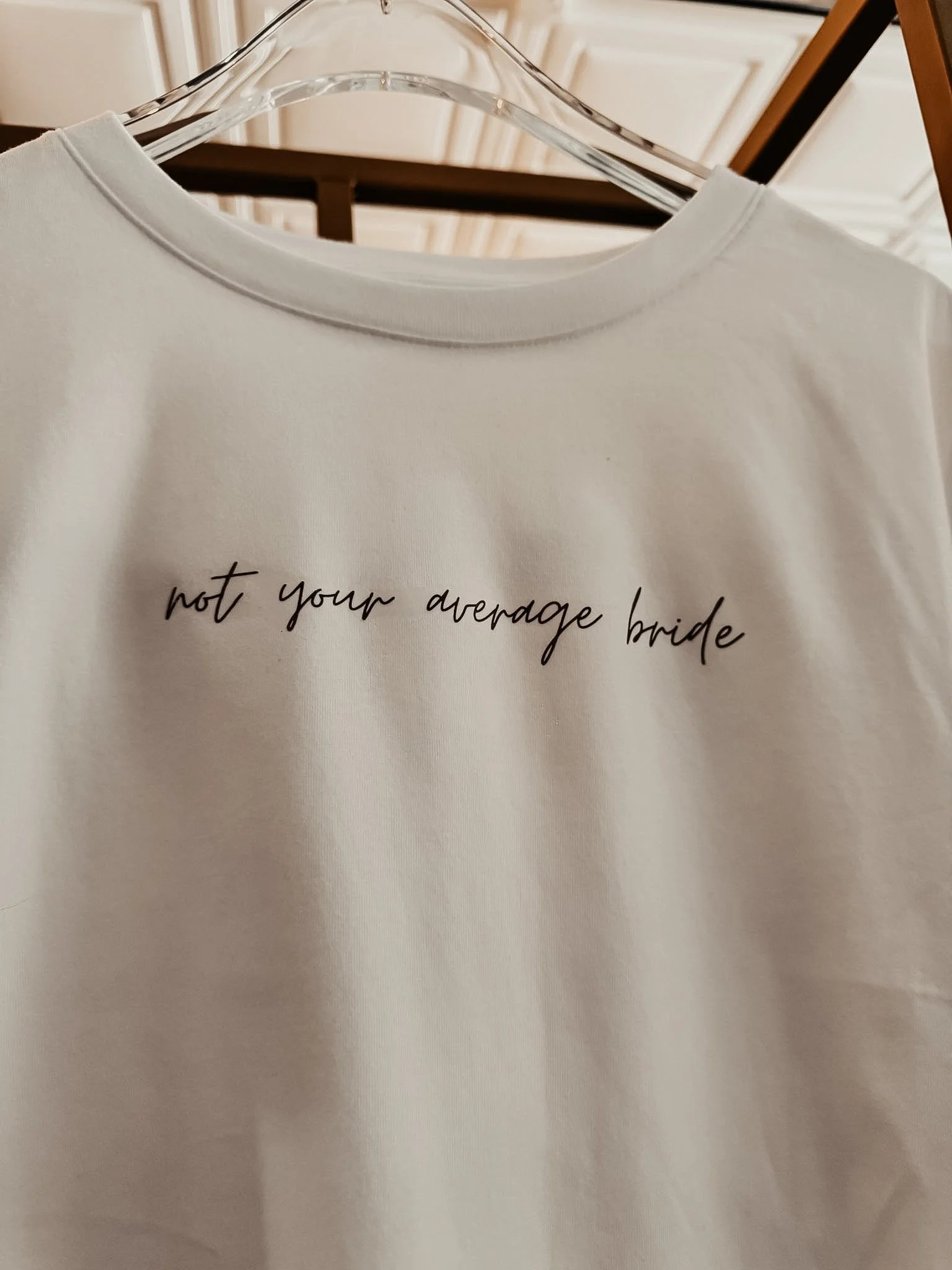 Not Your Average Bride Graphic Tee — a cream tee with hand-scripted "not your average bride" cursive graphic