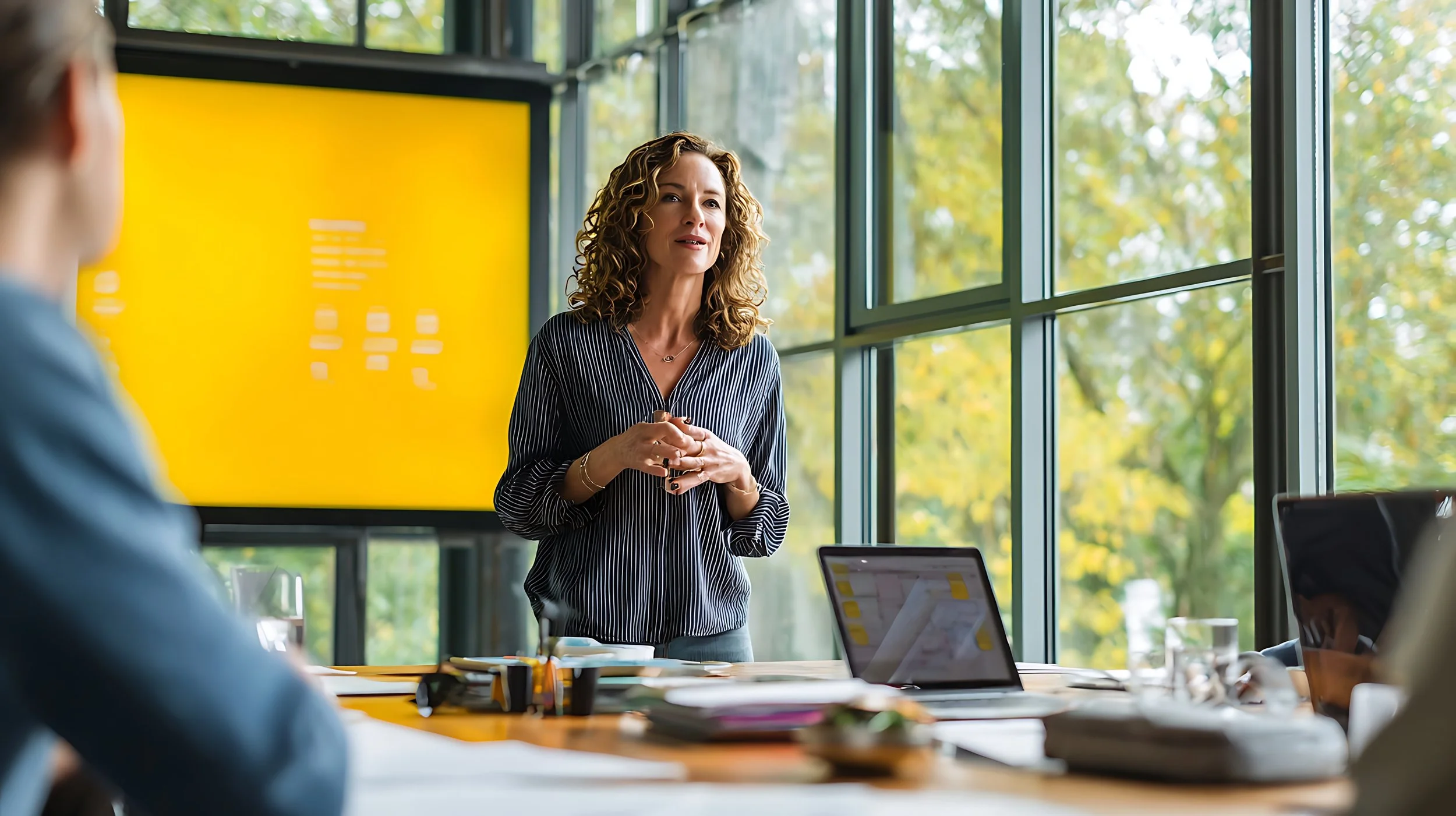 woman speaking to an audience with yellow screen behind her