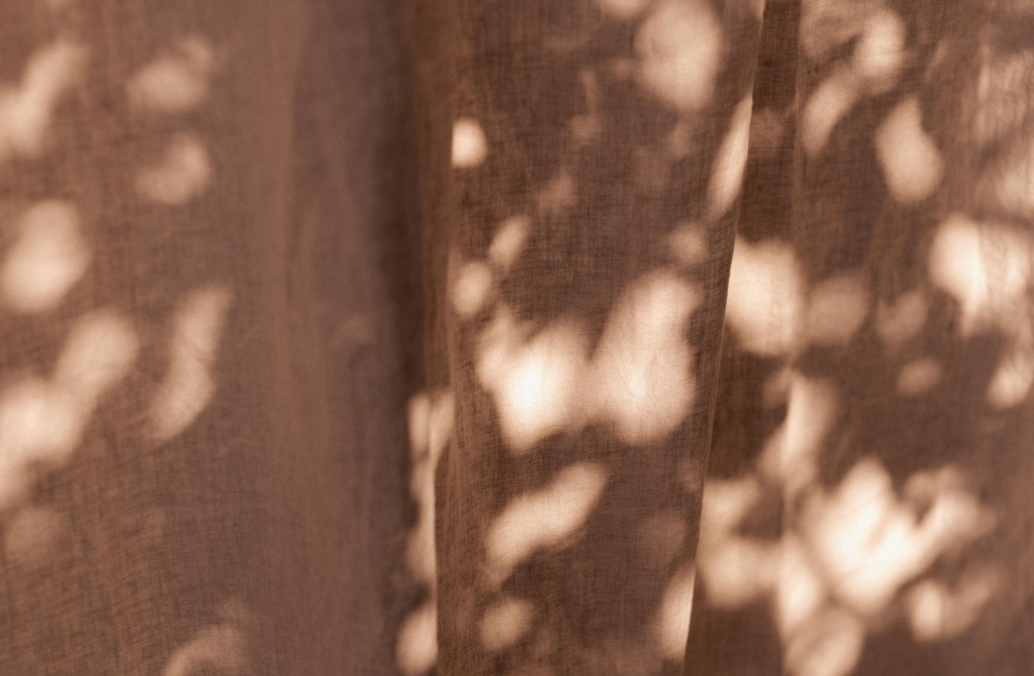 Close-up view of dark brown fabric with light-colored spots or patterns.