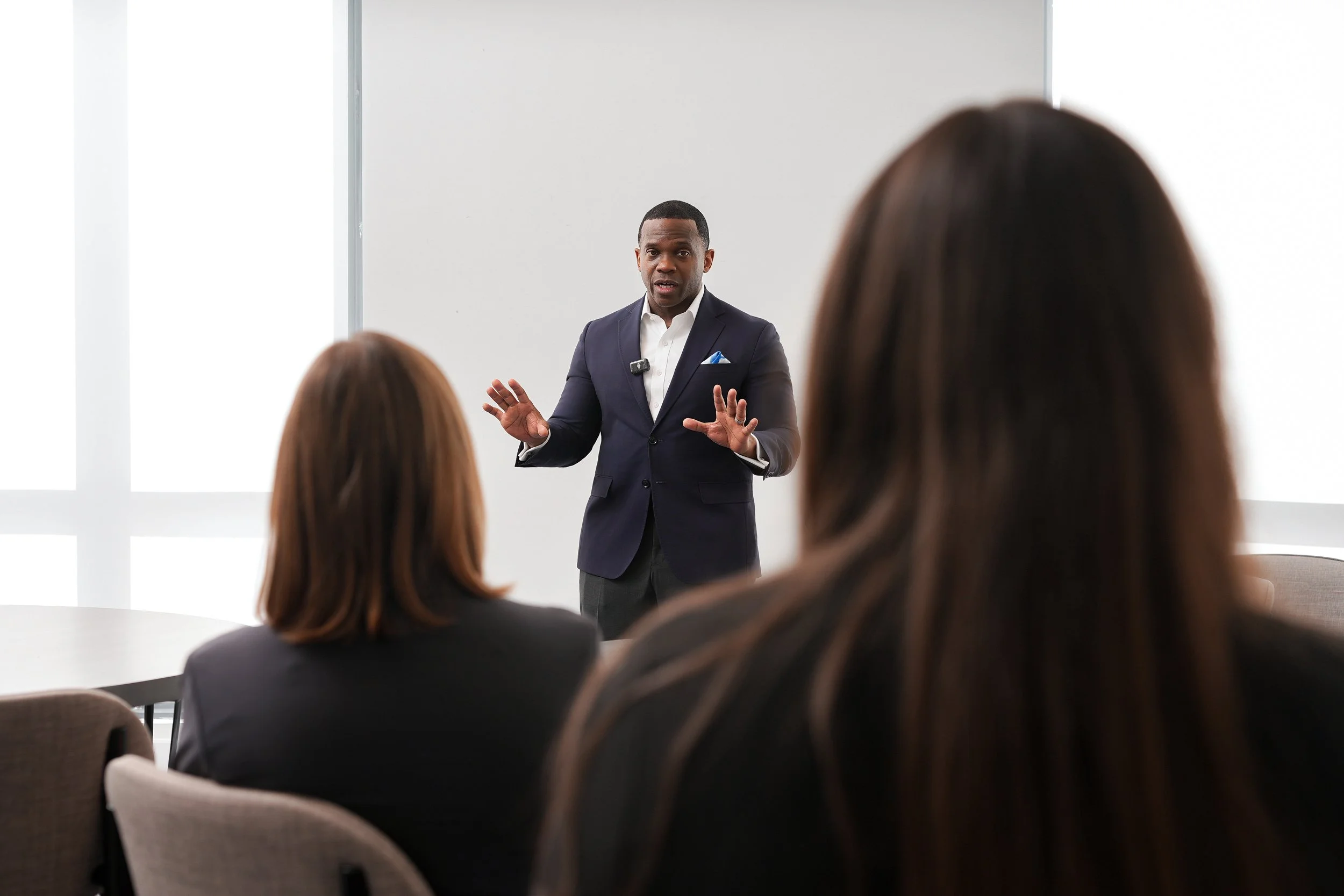 A man in a suit giving a presentation to a group of people in a conference room.
