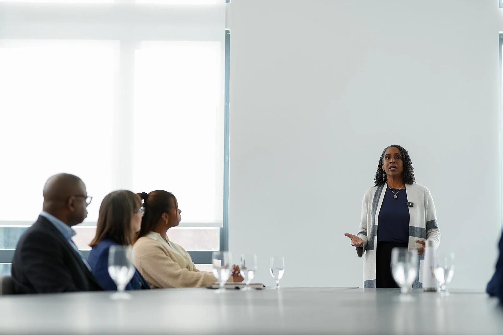 Woman giving a presentation to a group seated at a table.