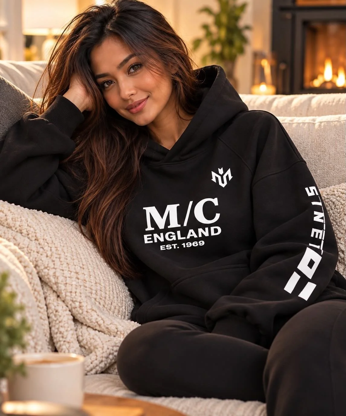 Woman relaxing on a sofa in a warm M.U.S.T. Fit® Sports 560 GSM heavyweight hoodie