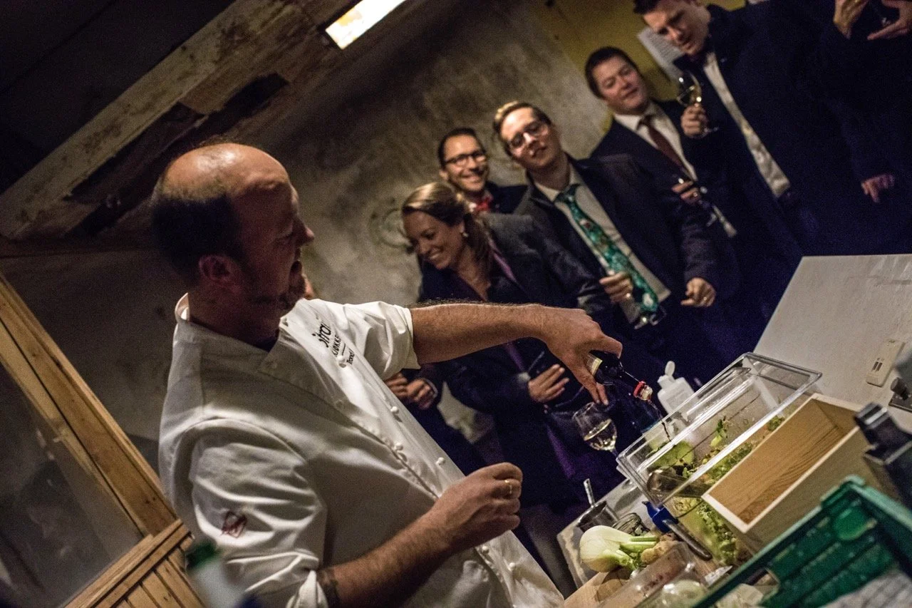 Kokk som demonstrerer matlaging foran gruppe mennesker på en restaurant eller bar