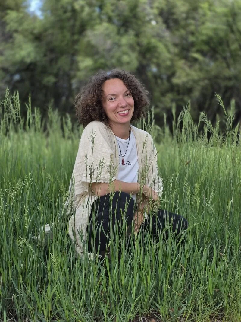 A woman kneeling in the grass and smiling