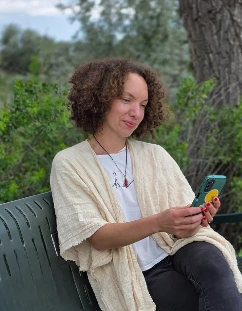 woman sitting on bench looking at phone and smiling