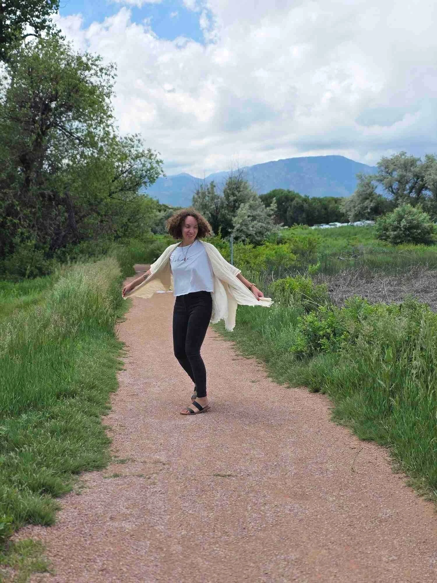 SEO copywriter and content marketing strategist, Stéphanie McGuirt, twirling on a trail surrounded by greenery with mountains in the background