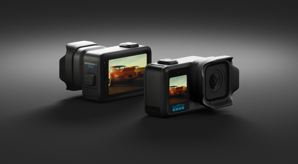Two GoPro cameras on a dark surface, one showing a car on its screen.