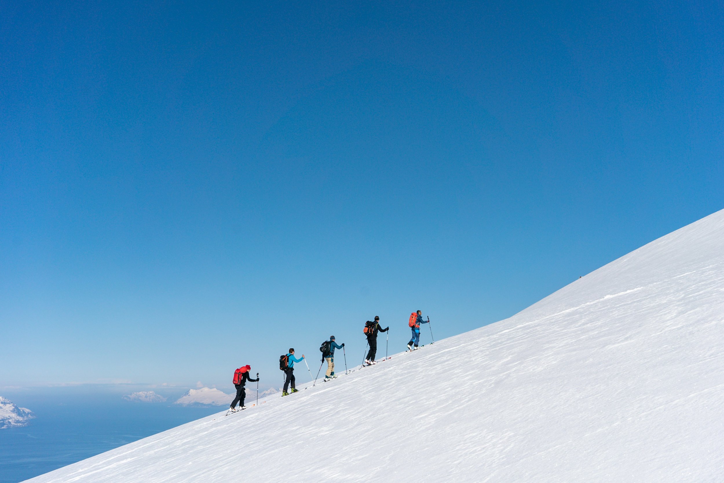 five hikers walking up a snow covered mountain