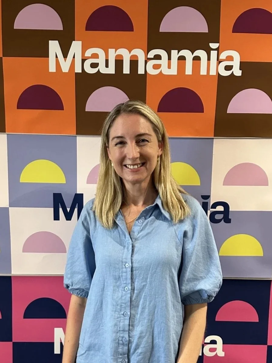 Woman standing in front of Mamamia sign. Minnie Collins