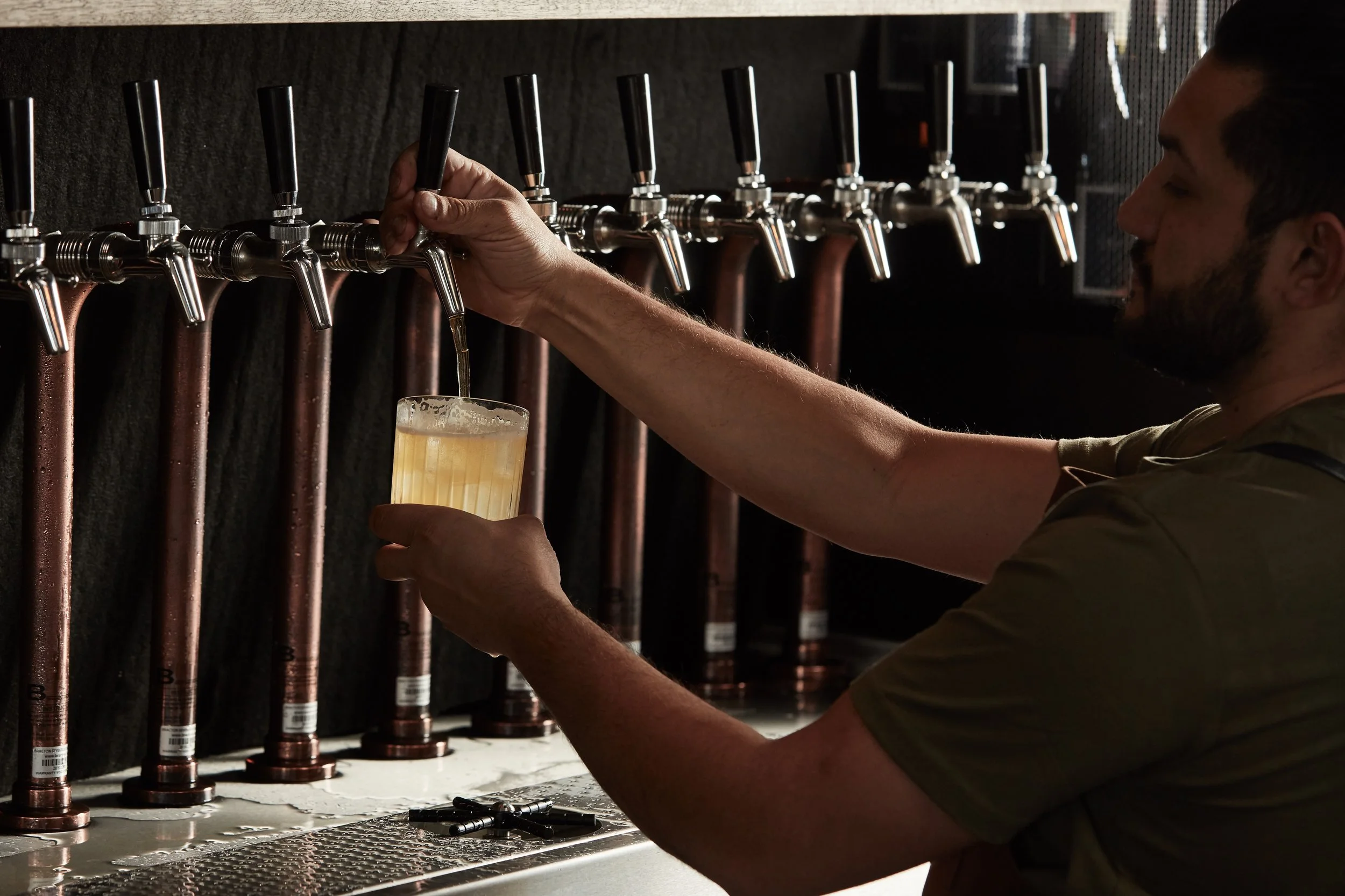 Person pouring beer from taps into a glass