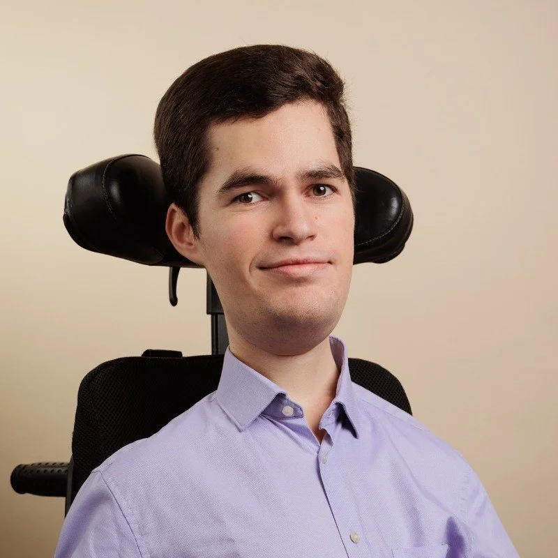 A picture of a man smiling in a mobility supporting chair