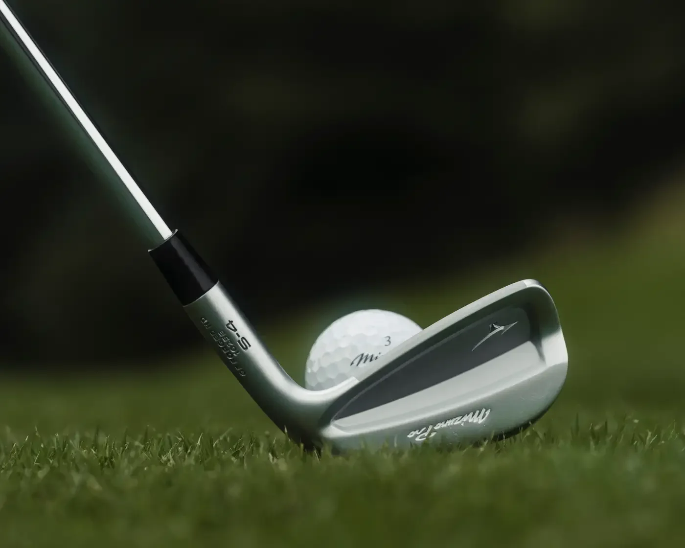 Mizuno Pro S-4 Eisen mit sichtbarer Cavity-Rückseite neben einem Golfball auf dem Rasen