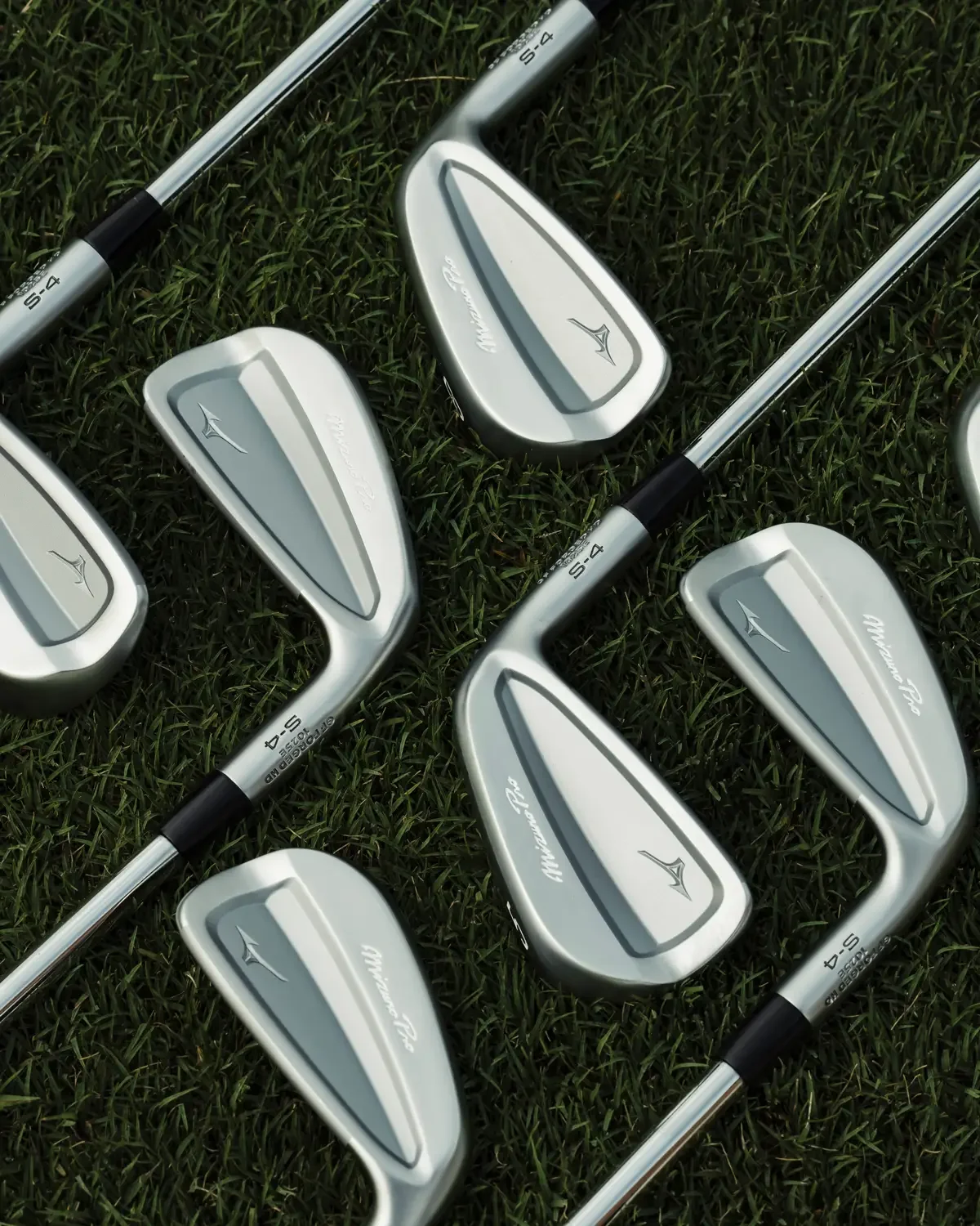 Mehrere Mizuno Pro S-4 Eisen auf Rasen – matte Kopfrückseiten und Cavity-Back-Design im Detail