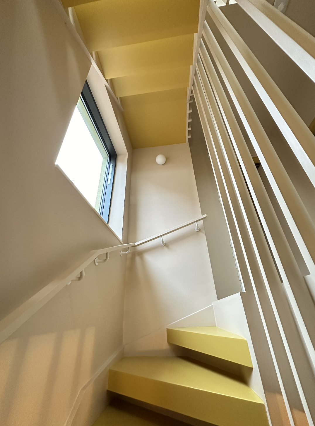 A yellow and white stairwell in a completed Surrey interior by Lime Grove Interiors.