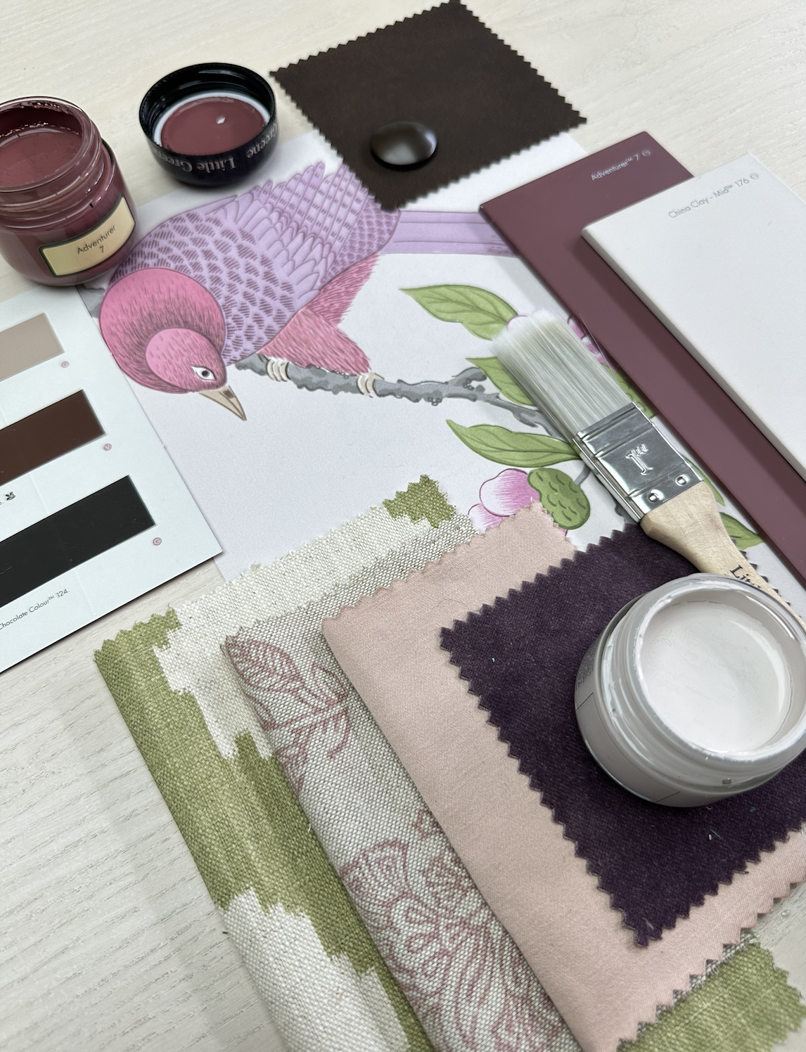 Interior décor and fabric samples arranged on a table with a pink bird illustration.