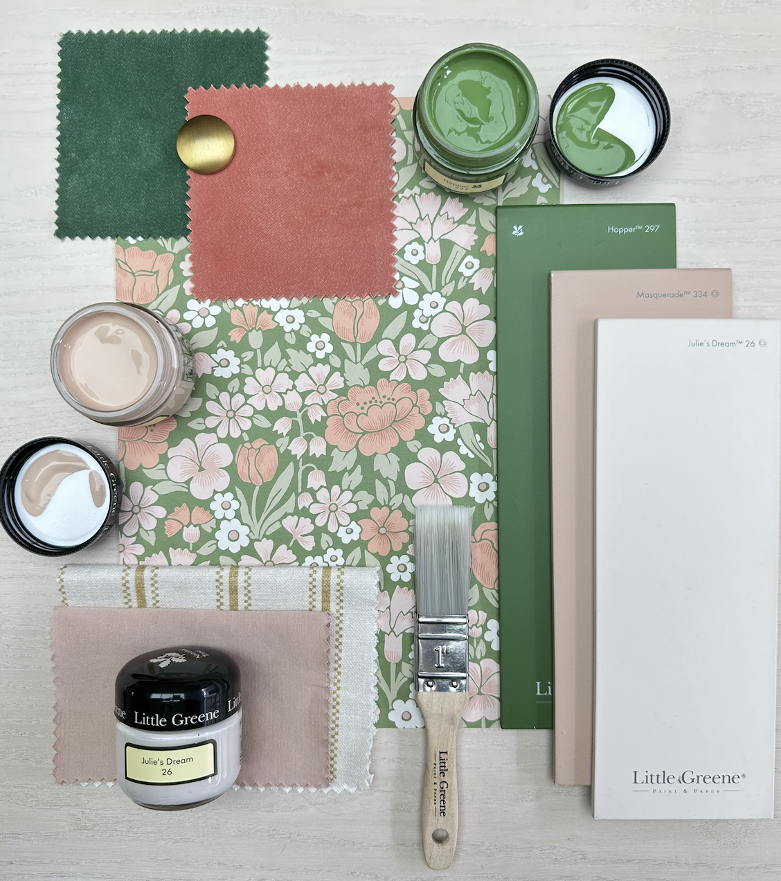 Painting supplies including colored paint, paint swatches, fabric swatches, a paintbrush, and color sample books arranged on a floral-patterned paper.