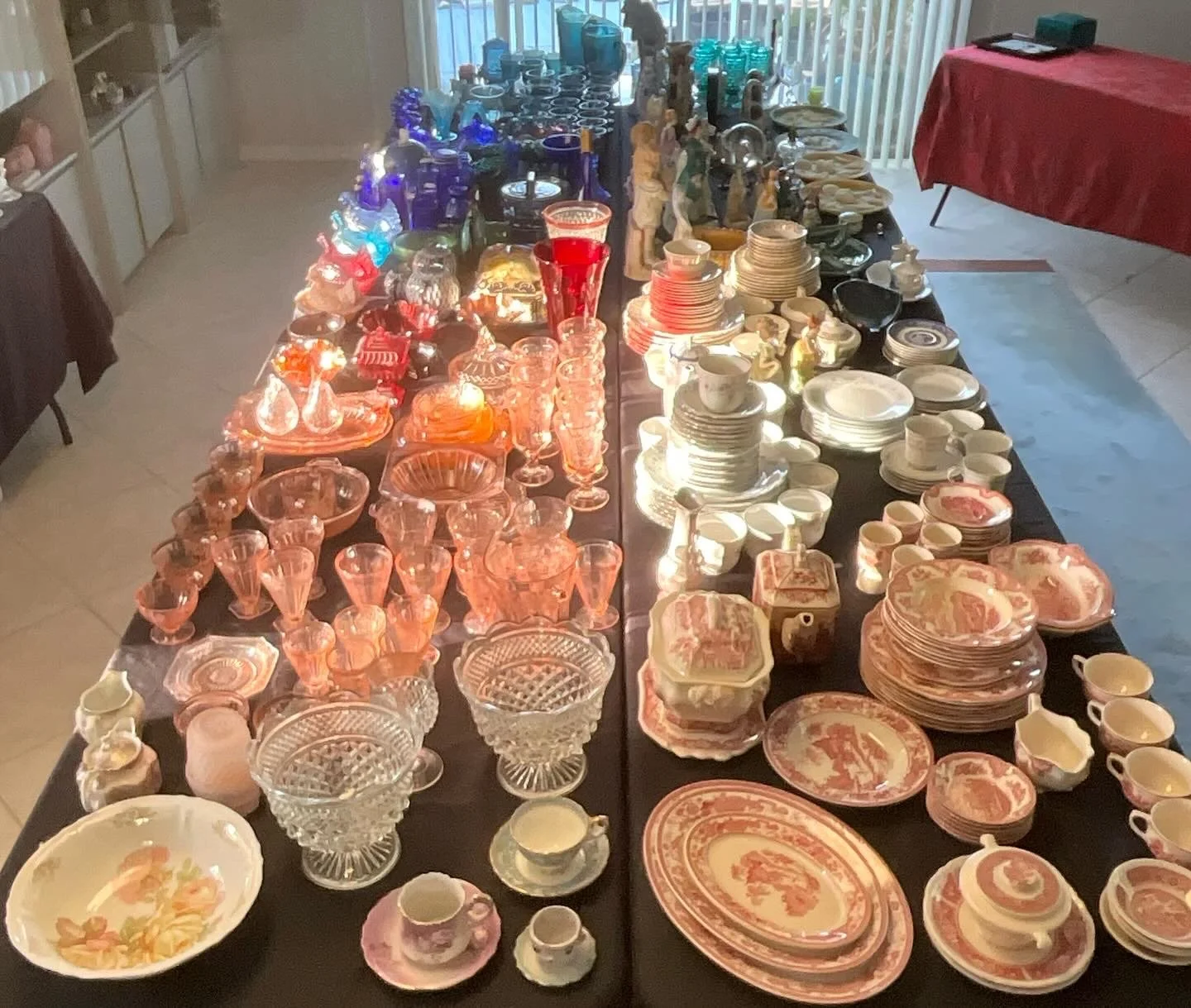 A table displaying various vintage glassware and china dishes, organized by color and type, with pink and orange glass pieces on the left and white and patterned china on the right.