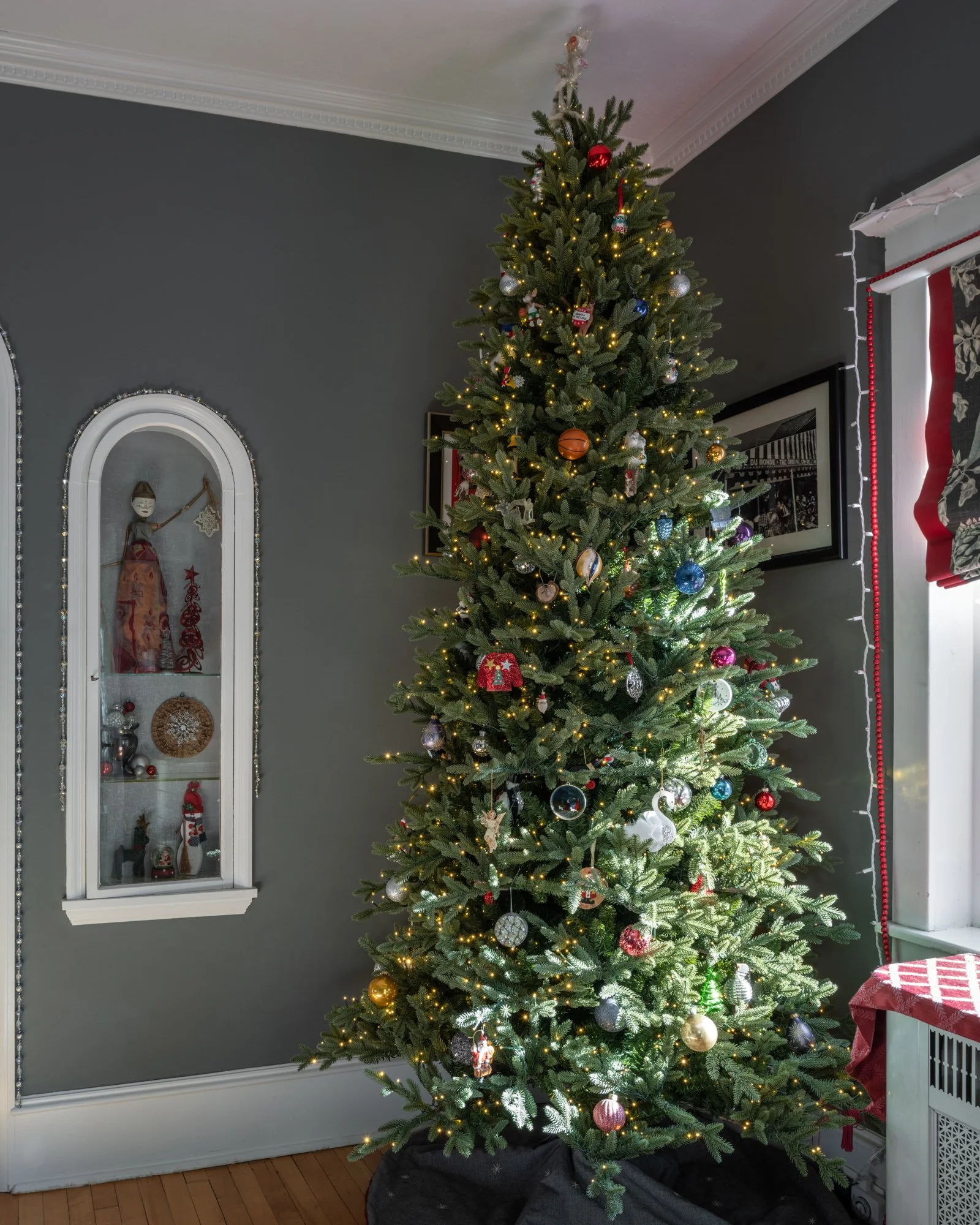 A decorated Christmas tree with lights and ornaments in a living room.