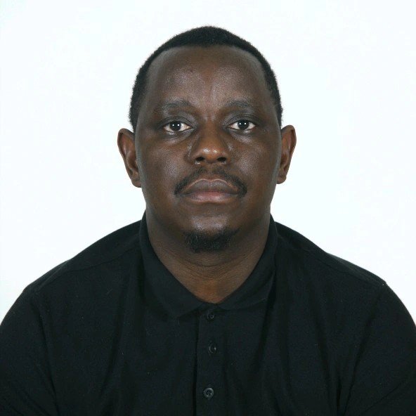 Portrait of a man with dark skin, short black hair, and a mustache, wearing a black shirt against a plain white background.