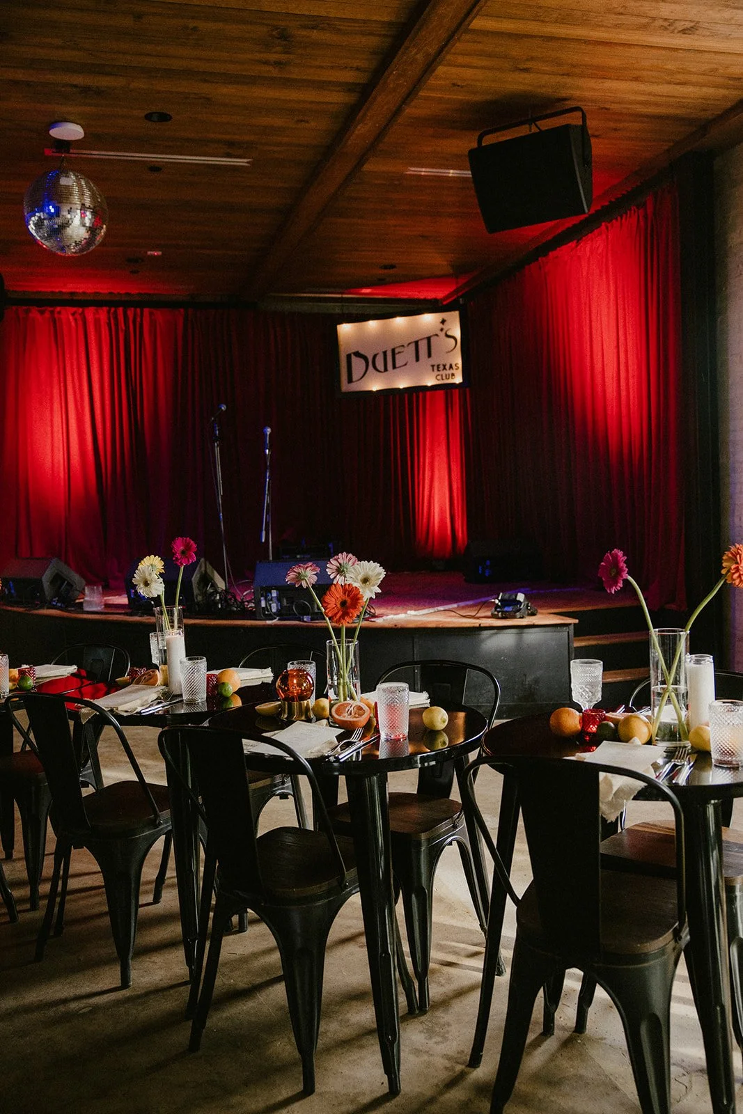 Dinner tables set with flowers in front of the stage at Duetts Texas Club.