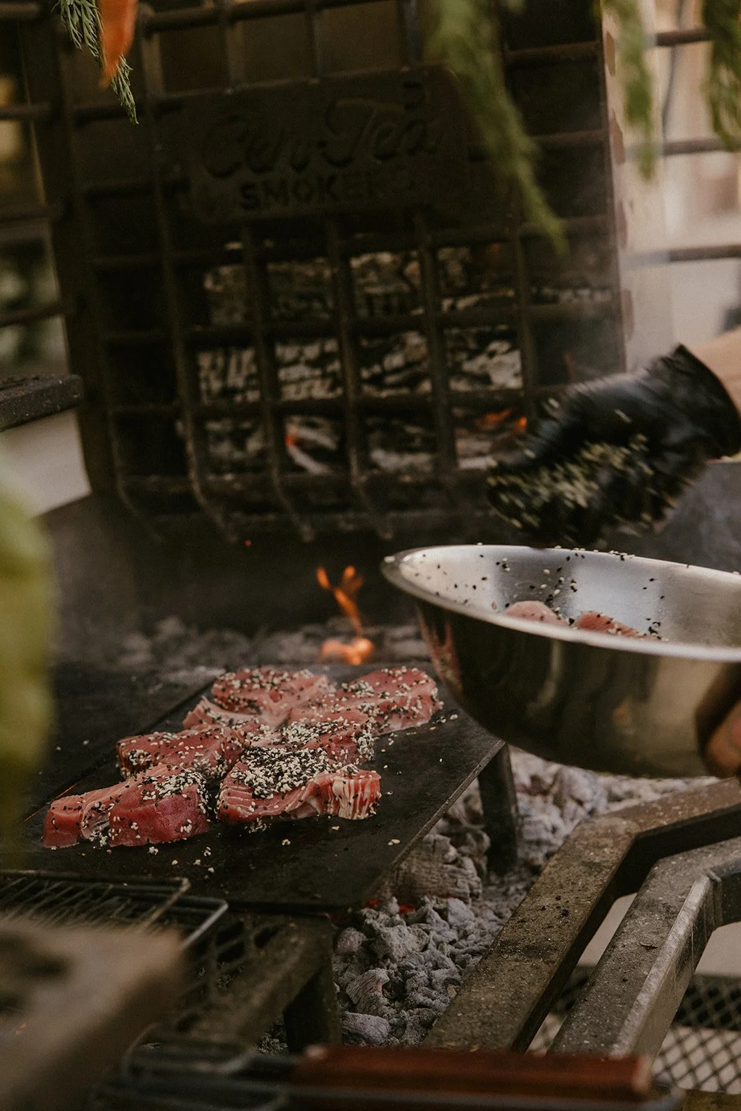 Sesame-coated fish cooking over a live fire for an event meal.