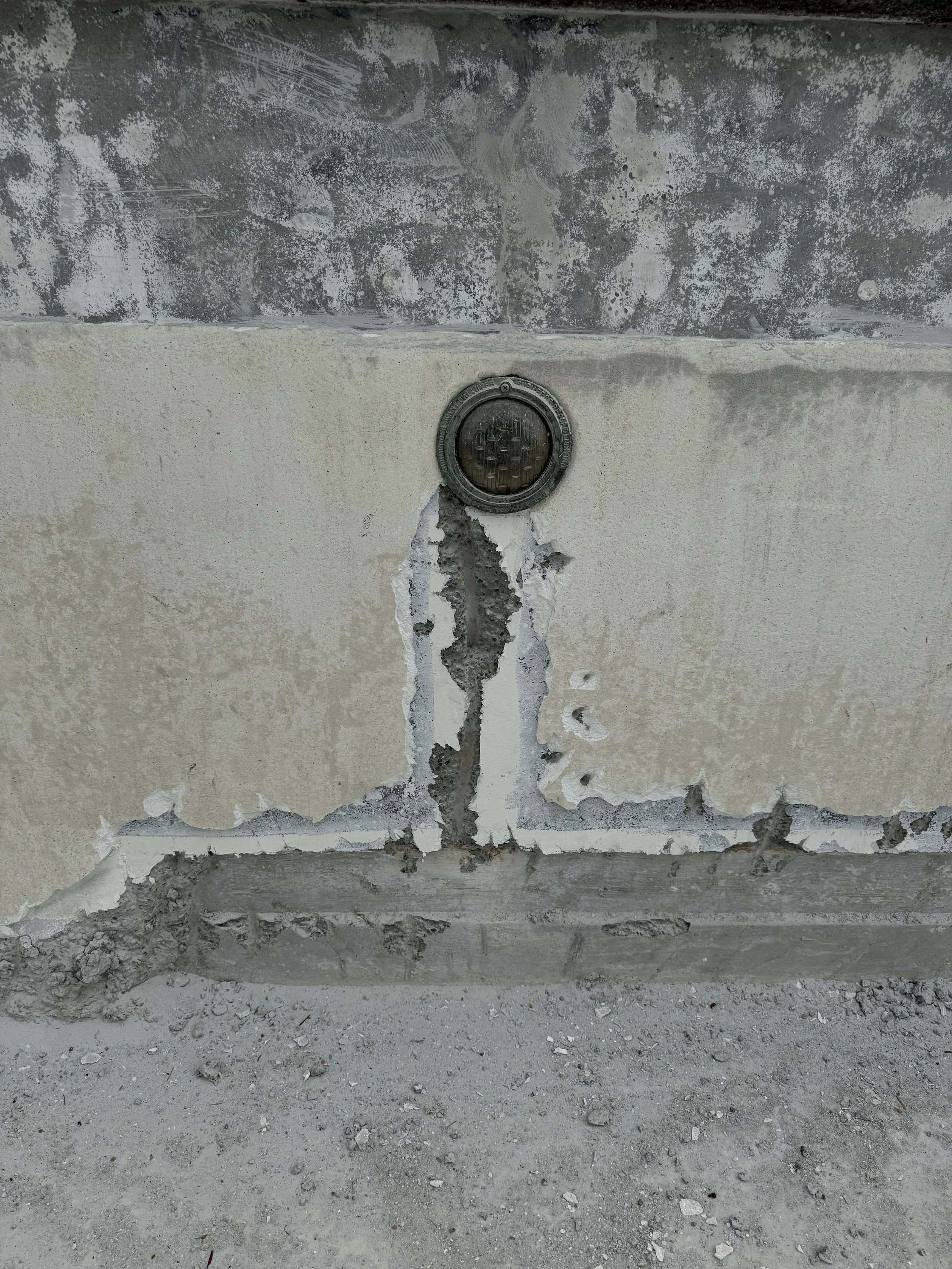 Concrete wall with visible cracks leading up to a pool light niche.