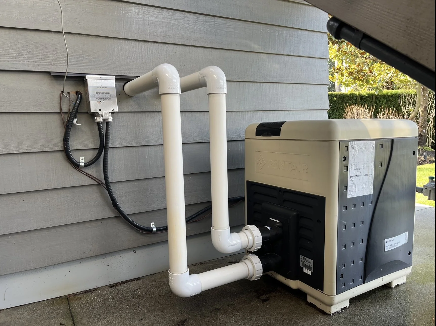 Pool heater with PVC pipes and electrical connections on exterior wall