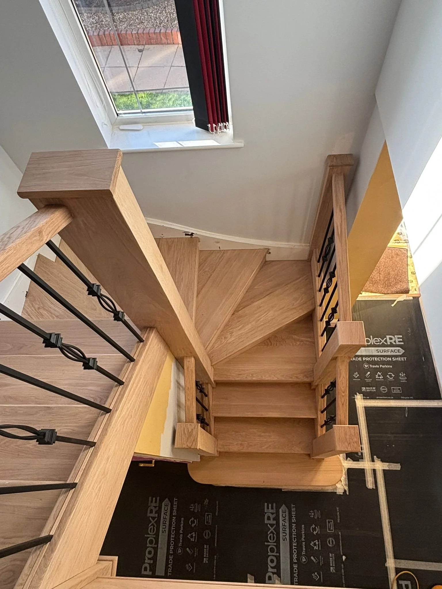 stair cladding on a staircase featuring black metal spindles and a corner window. we have renovated the floor and laid floor protection in North Bristol, Winterbourne