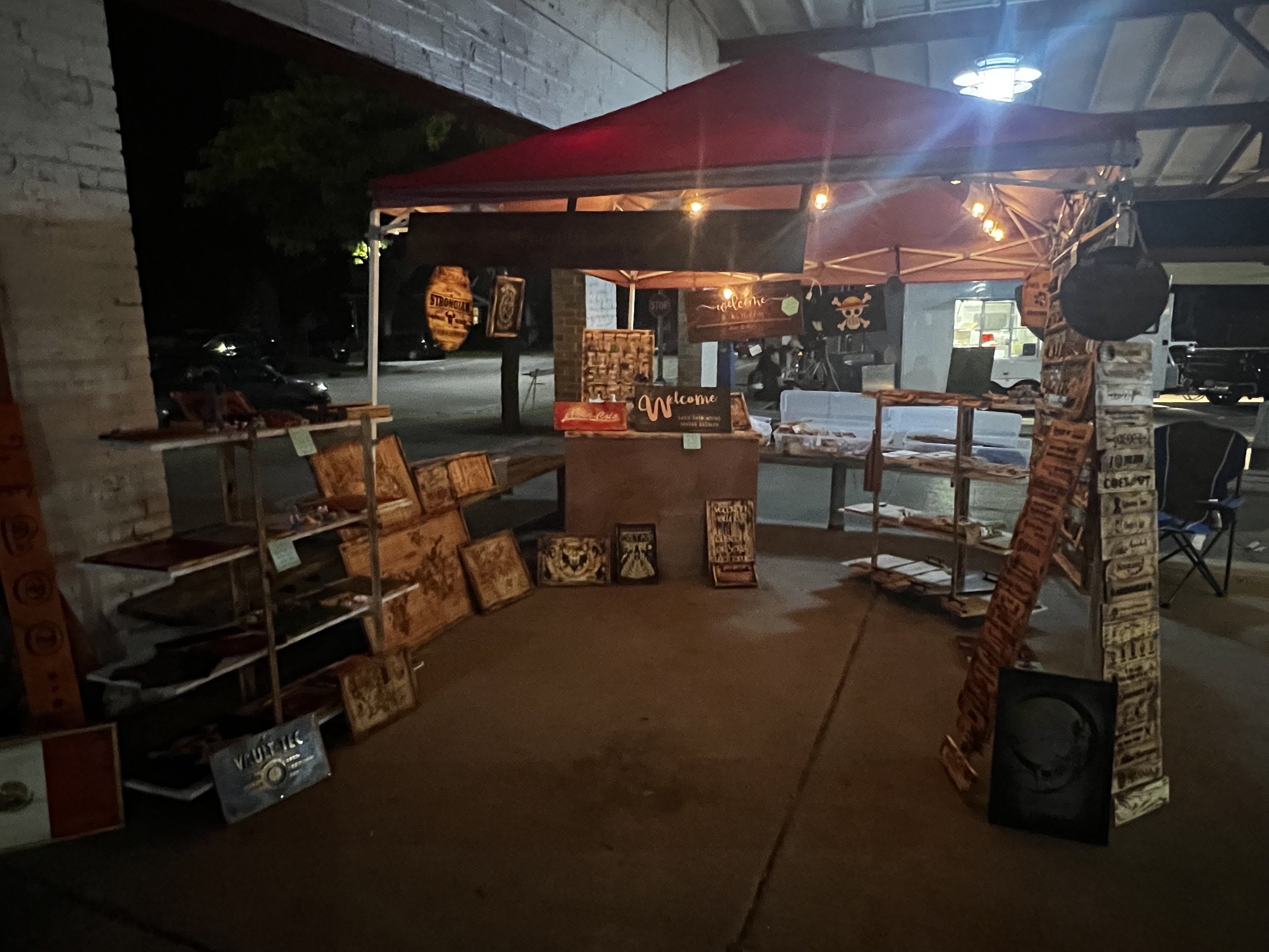 Outdoor market stall with wooden signs and crafts displayed