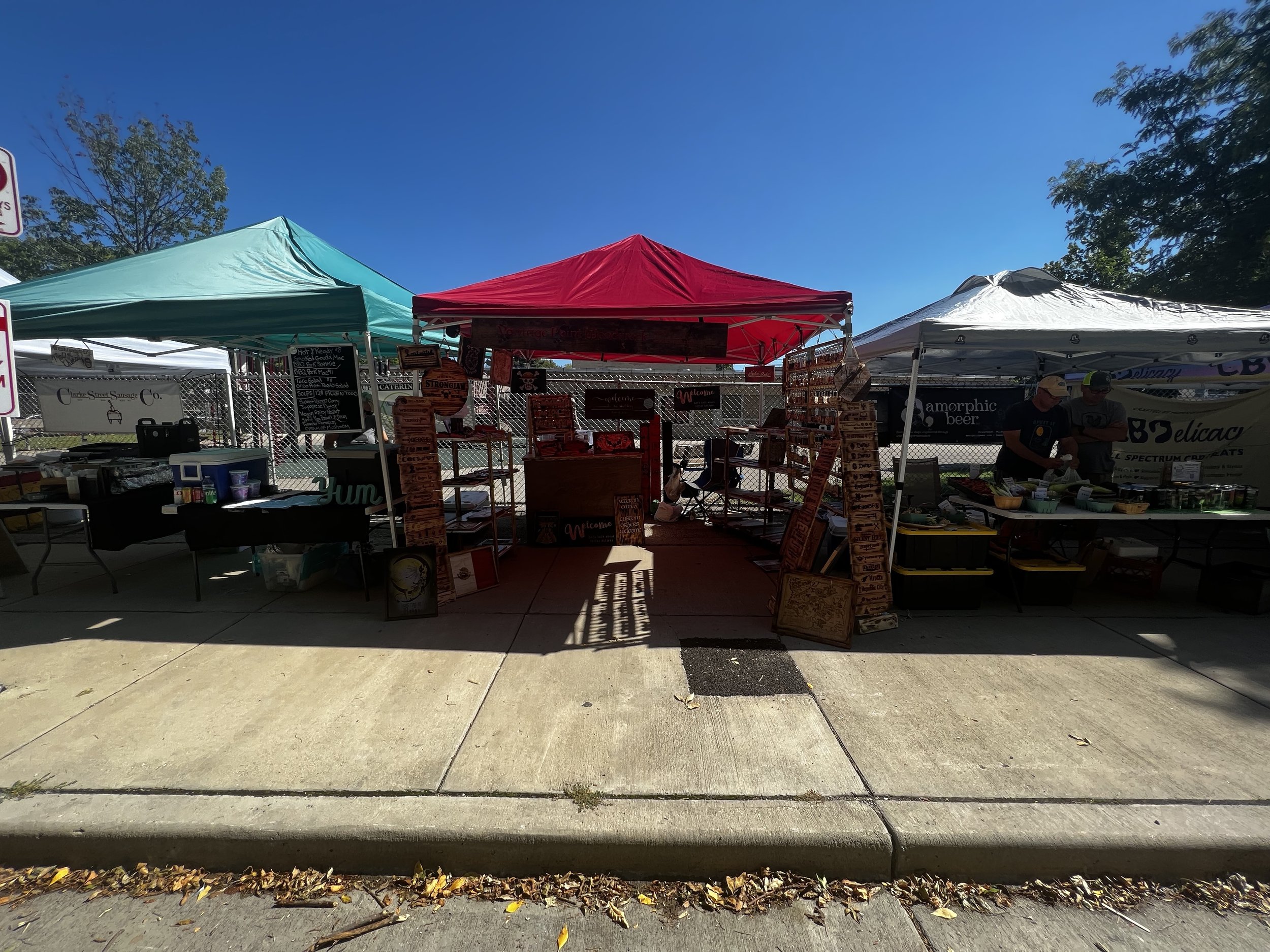 Outdoor market with tents, displaying various food and merchandise