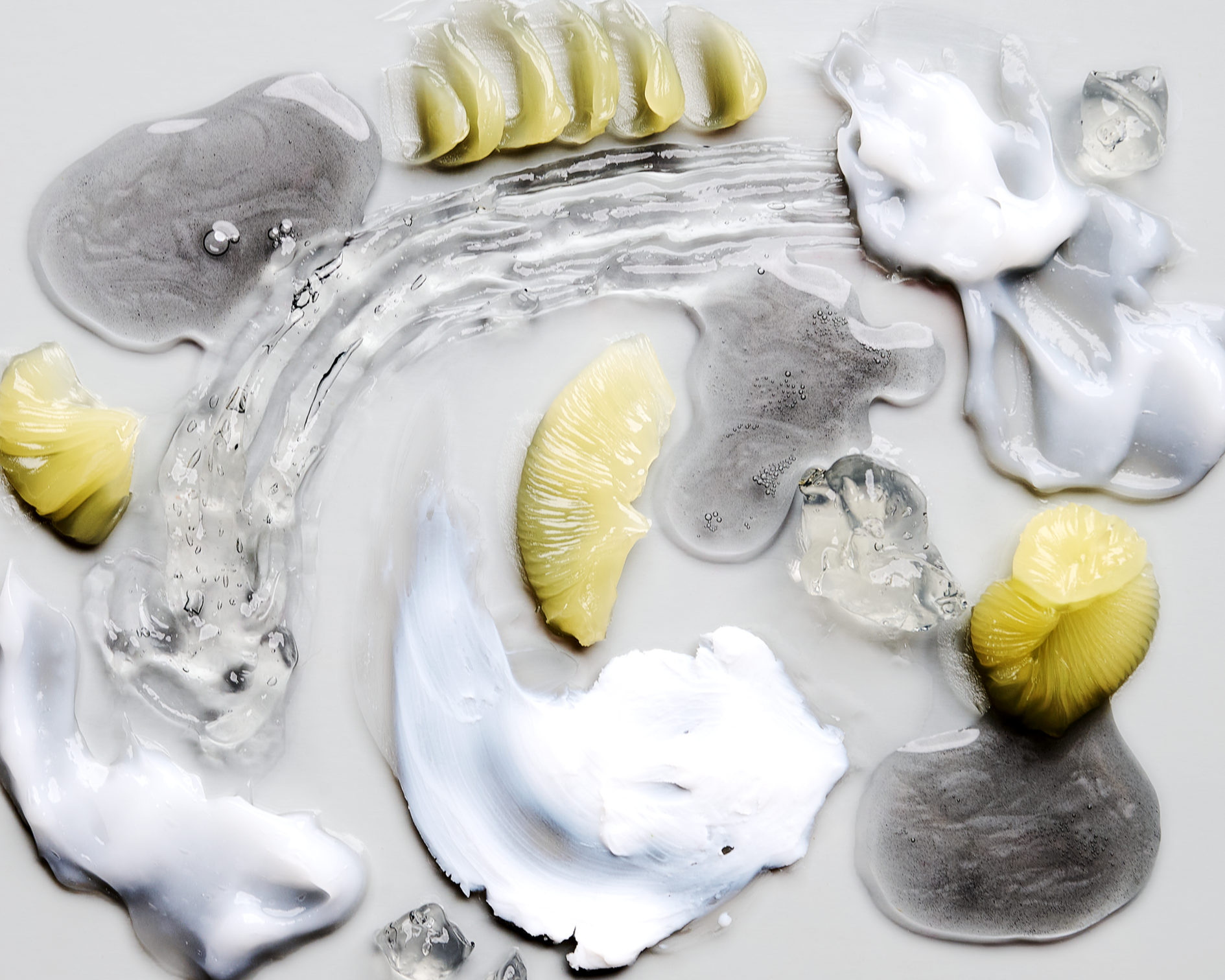 Slices of lemon, blobs of cream, pieces of ice, and large gray stones on a white surface.