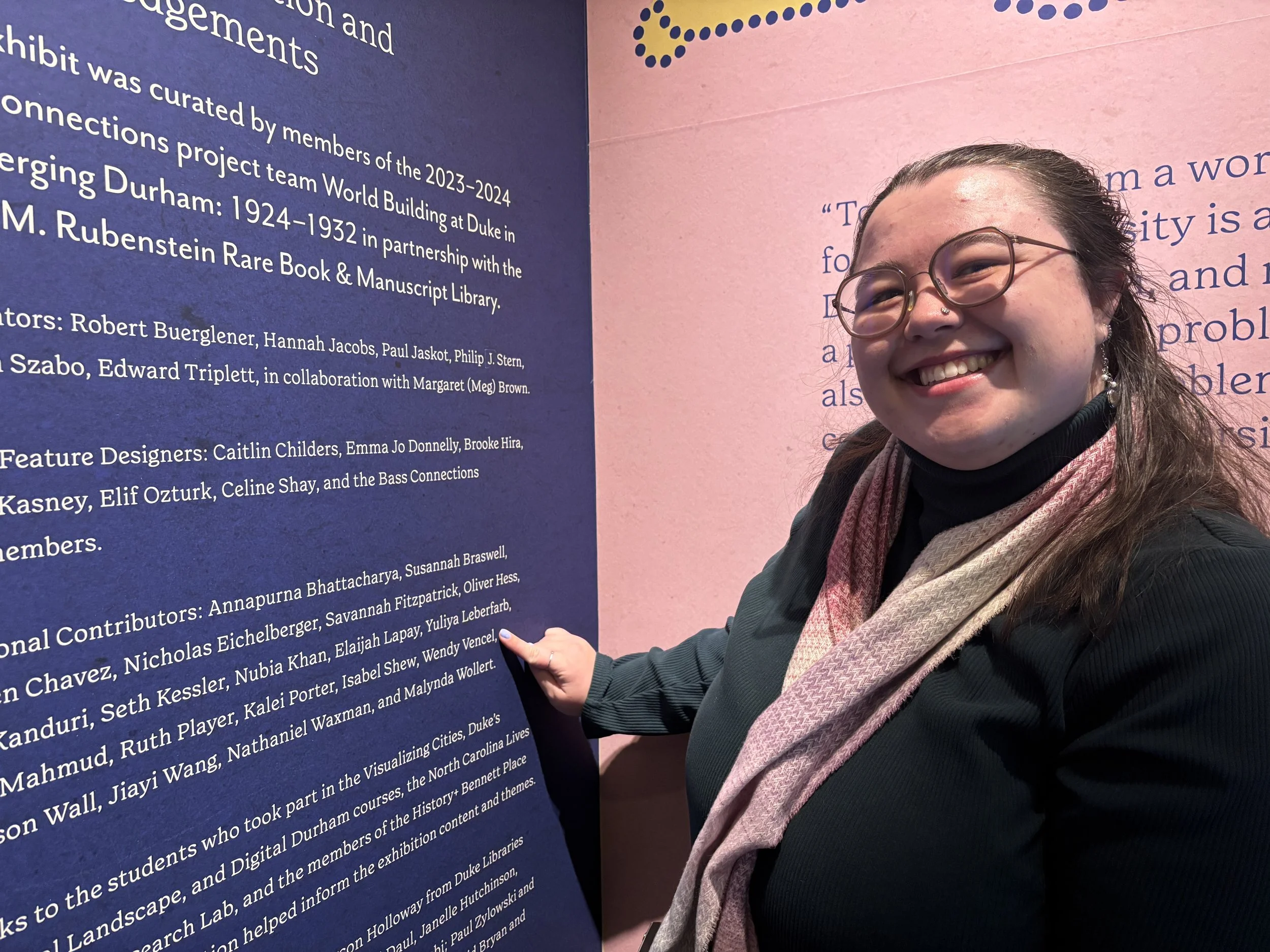 Wendy pointing to her name listed as a contributor for an exhibition at Duke University in Spring 2025. 