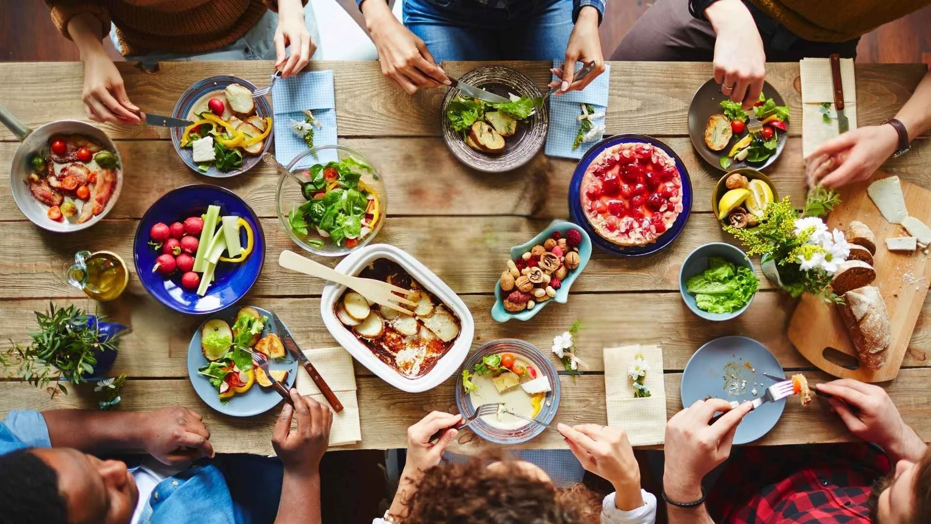 People sharing food together around a table, representing hospitality and cultural connection.