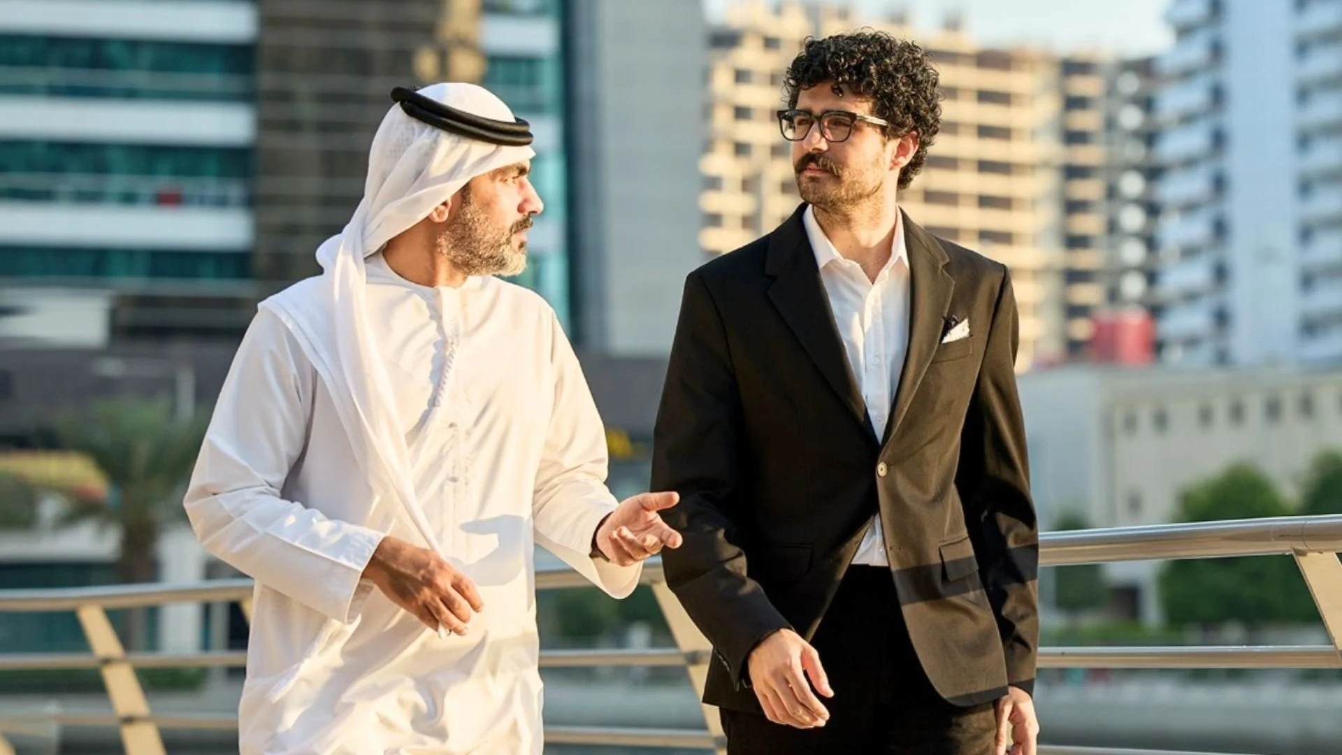 Arab colleague having a friendly conversation with a non-Arab colleague before a home invitation.