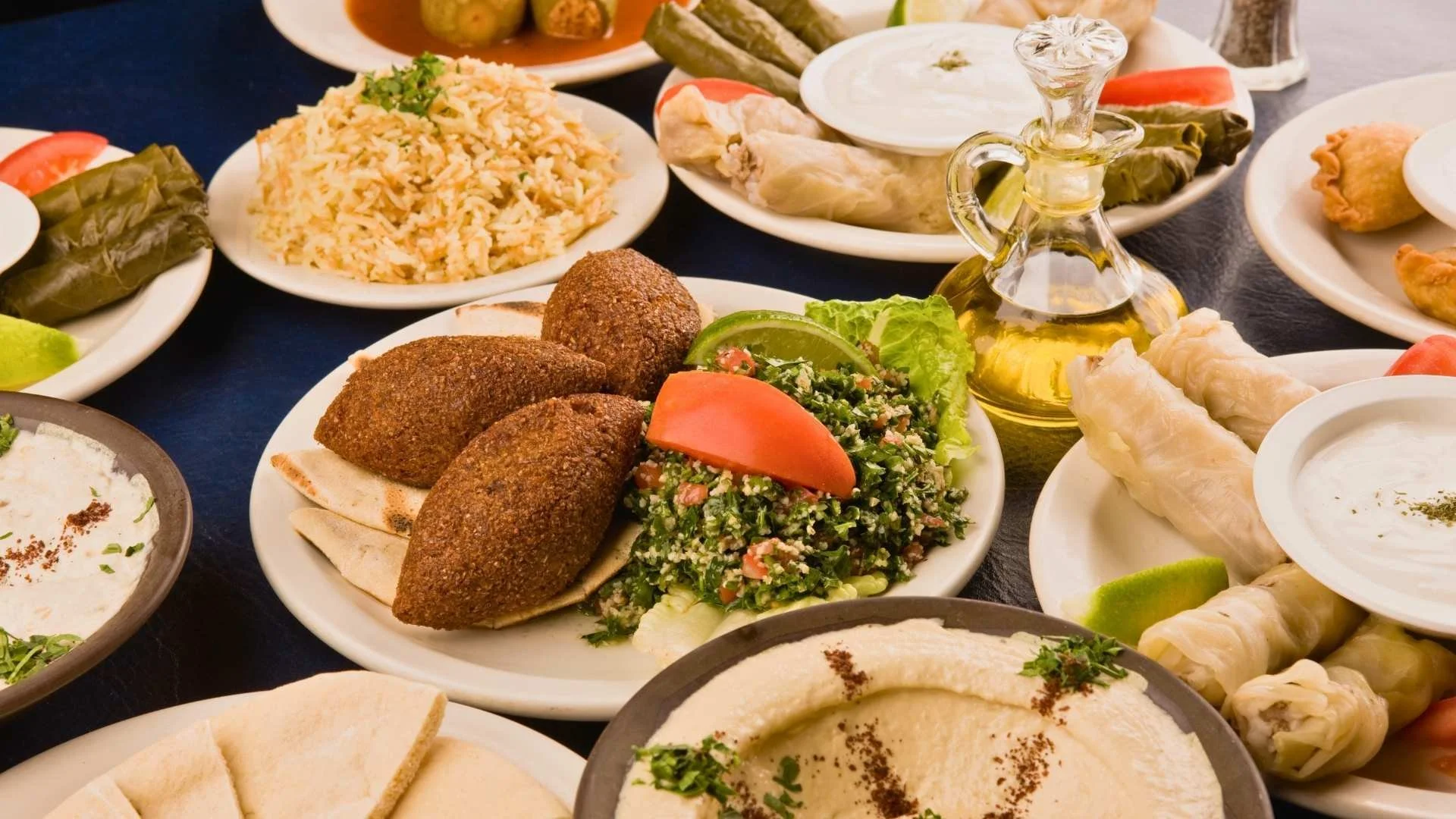A generous Arabic food spread with mezze, rice, bread, dips, and shared dishes.