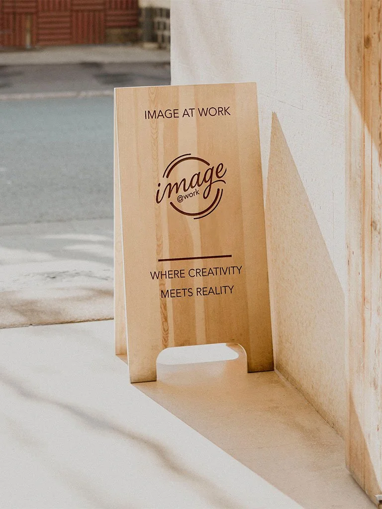 Wooden sign outside a building with the words "Image @Work" and the phrase "Where creativity meets reality" printed on it.