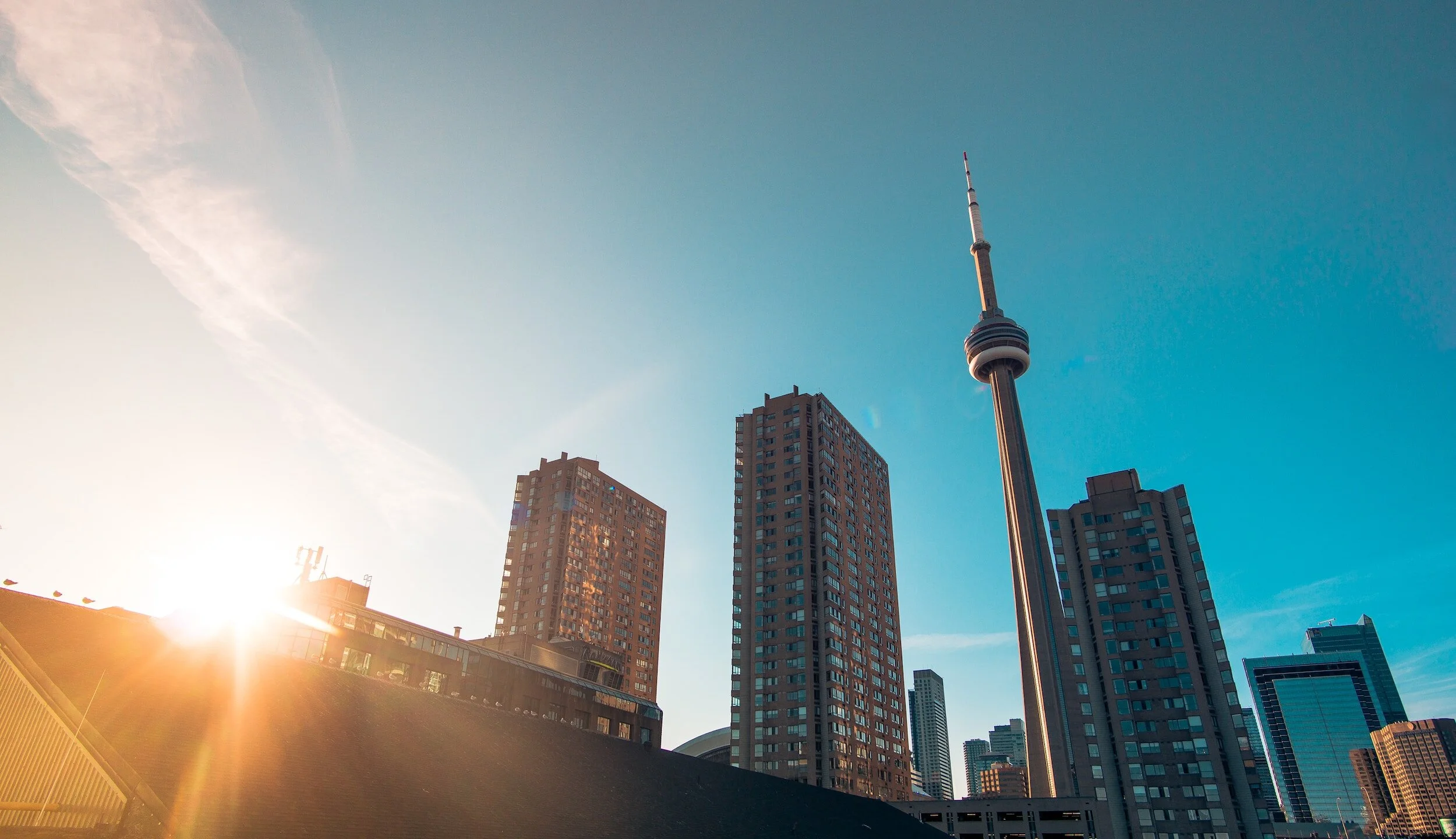 Skyline of Toronto featuring the CN Tower, with buildings and sunlight in the foreground.