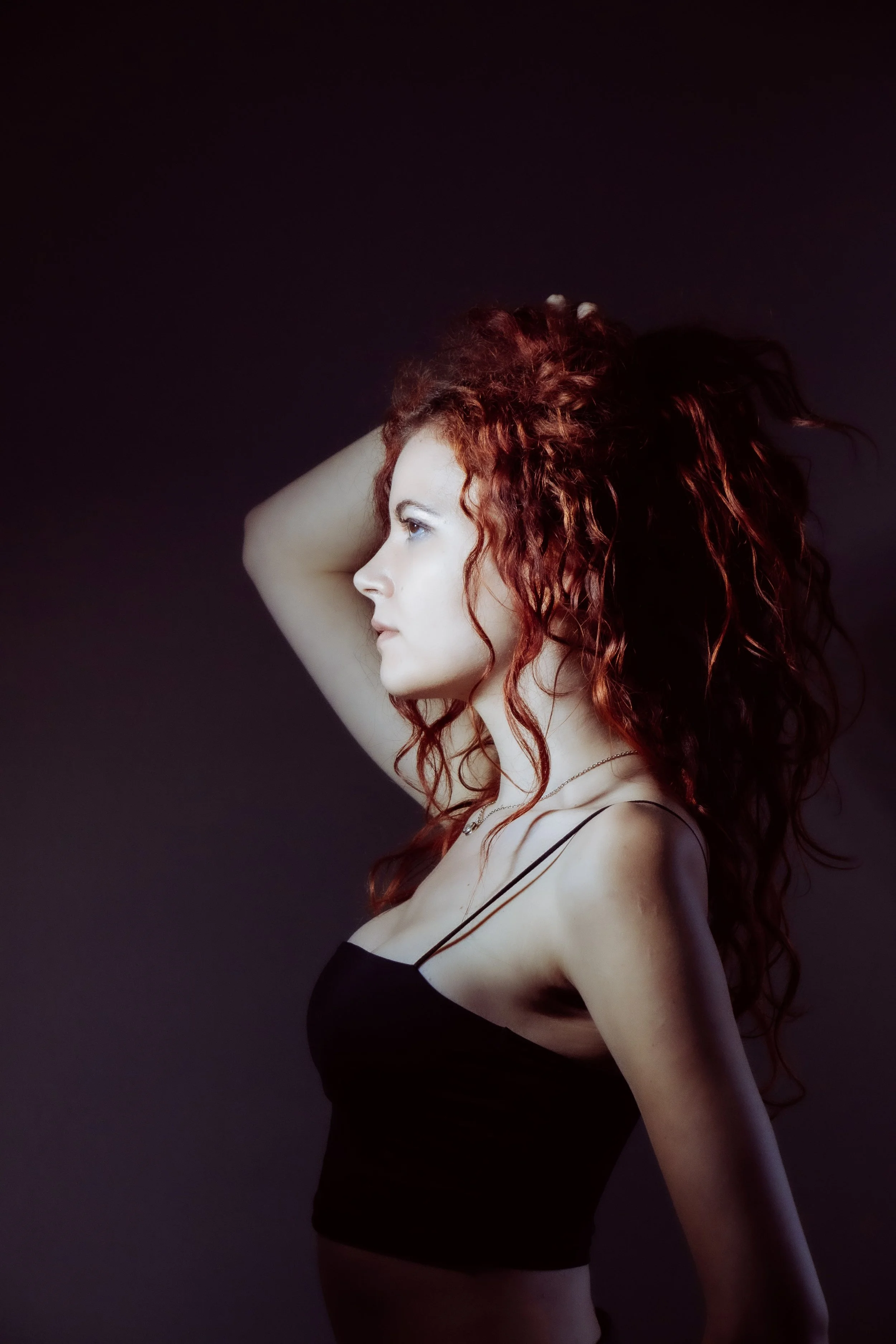 Portrait minimaliste d’une femme rousse en studio. Éclairage doux et pose élégante.