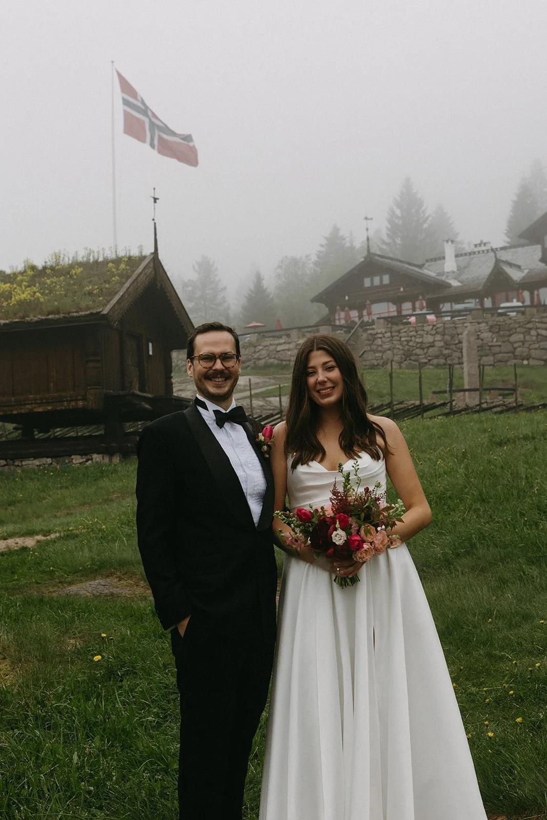 Bride and Groom standing happily together in Misty Weather with the Norwegian Flag in the background