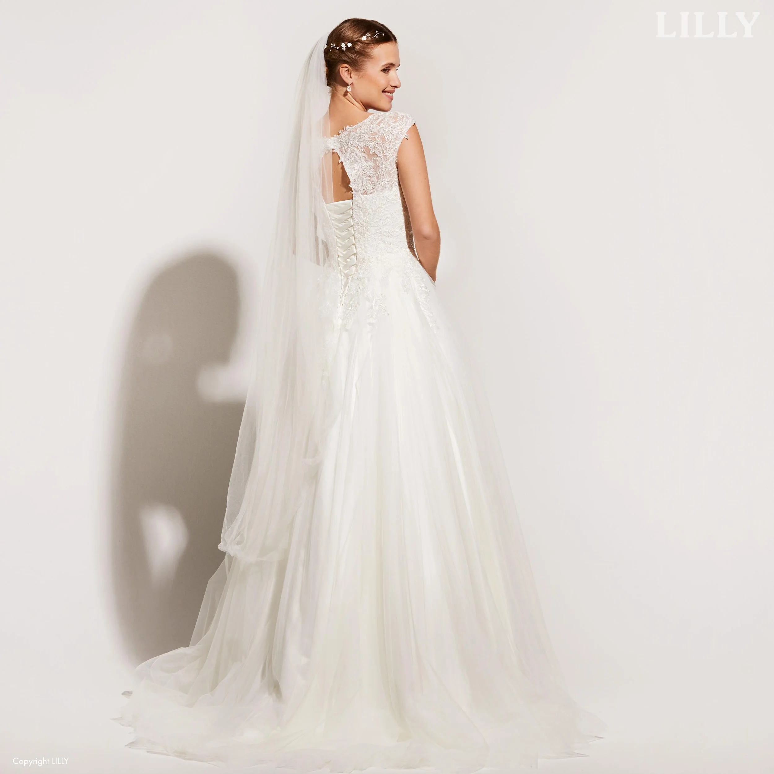 Nydelig brudekjole med glitrende blondedetaljer og tyllskjørt, og nøkkelhullåpning i ryggen. Denne har praktisk snøring i ryggen, og det er en av våre nye brudekjoler fra Lilly. 