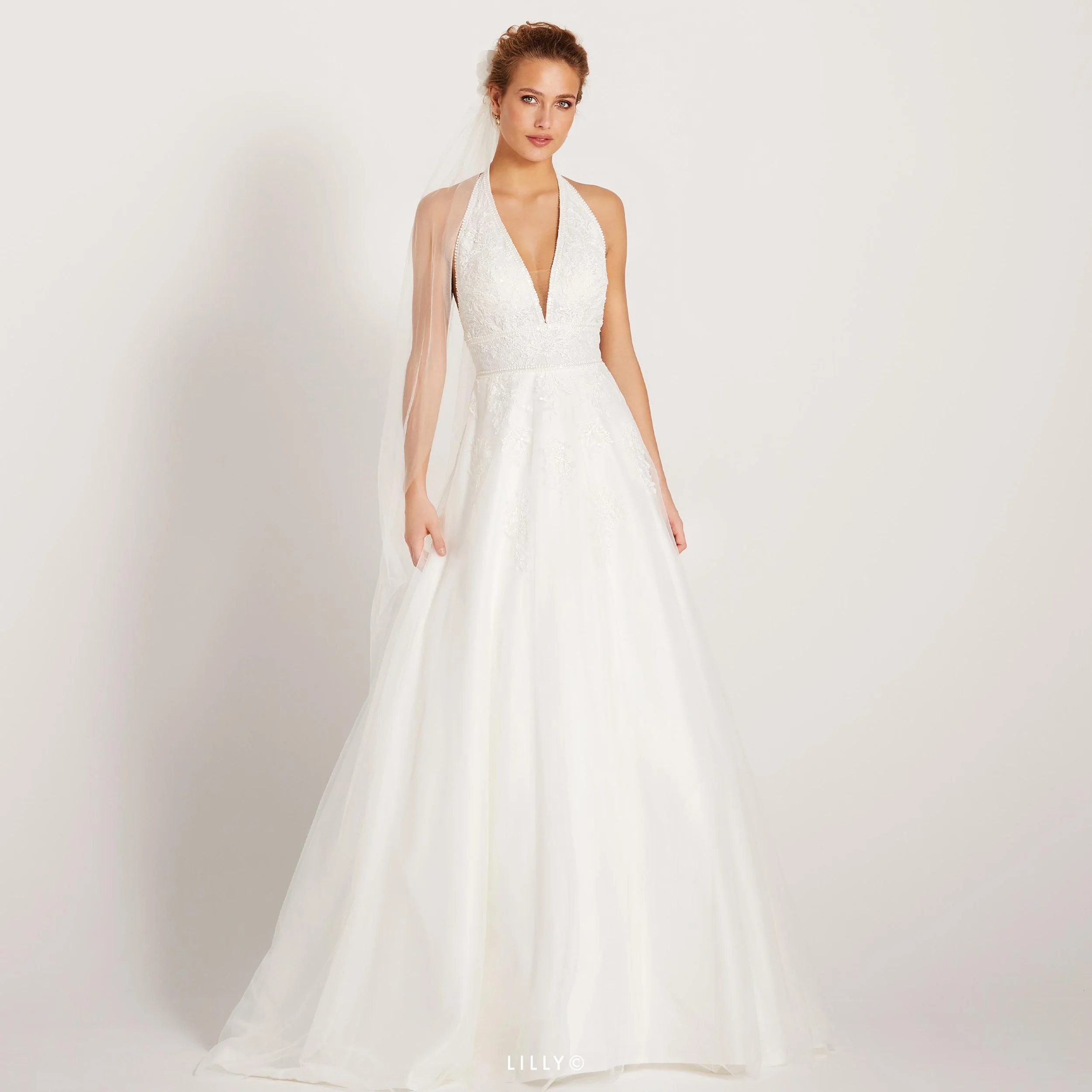 For deg som liker åpen rygg har vi denne lekre halterneck brudekjolen fra Lilly.  overdelen er i en vakker blonde og har et lett dryss av paljetter. Tyllskjørtet har også lekre blonder  nedover, og dette er en av våre nye brudekjoler.