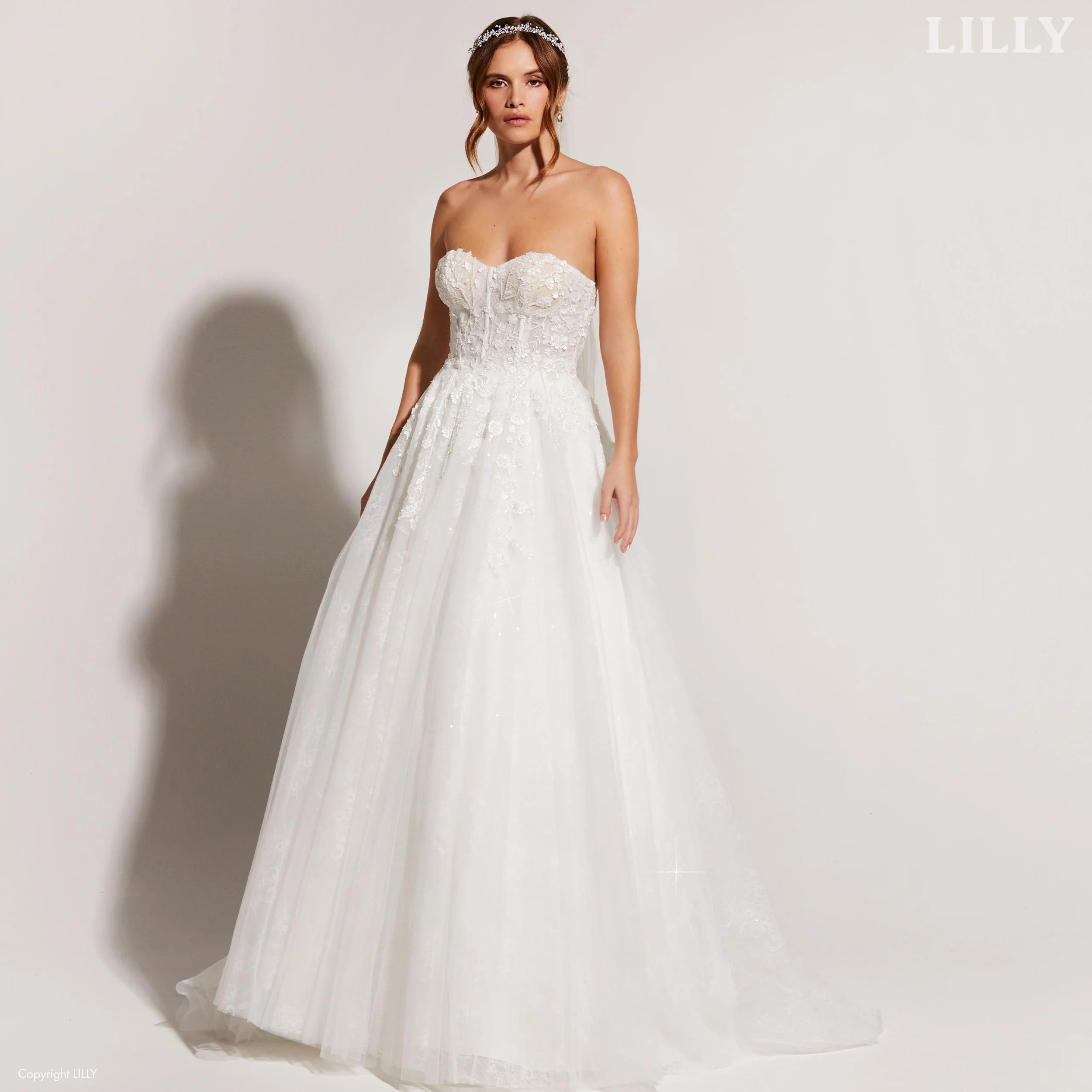 Nydelig brudekjole med korsettliv og snøring i ryggen, tyllskjørt med blonder og glitrende detaljer. Dette er en av våre nye brudekjoler, og den er fra Lilly. 