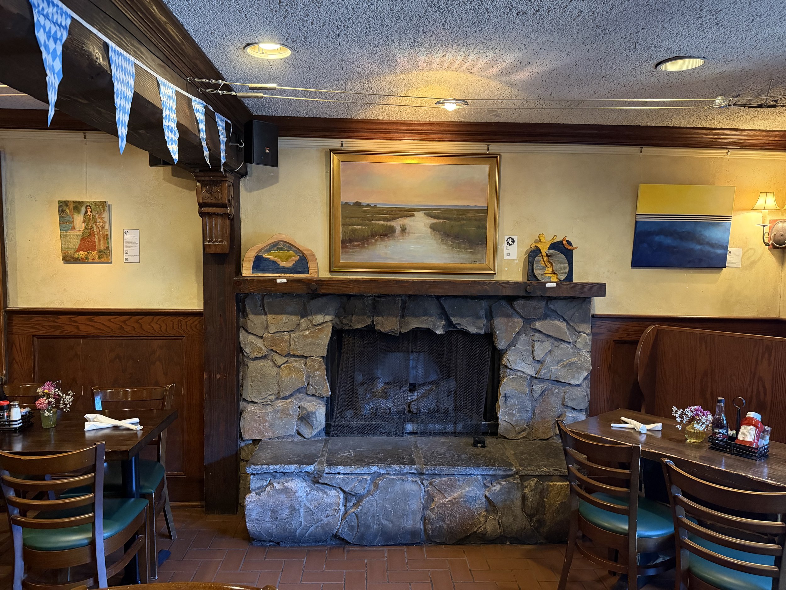 Paintings by Safoura Haghighi on the left, Layla Gray in the Center, and Monique Leahy on the right, with wood sculptings by Mike Long adorning the fireplace mantel