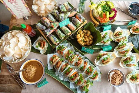 Buffet de plats asiatiques, notamment des rouleaux de printemps, salades, sauces, et desserts.